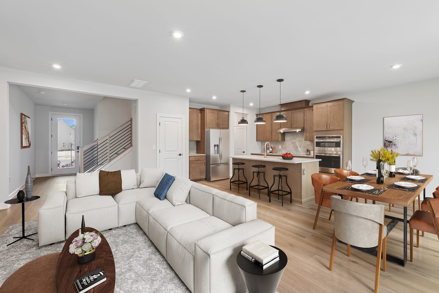 A modern, open-concept living space with a kitchen, dining area, and living room, featuring a white sofa, wooden furniture, and pendant lighting.