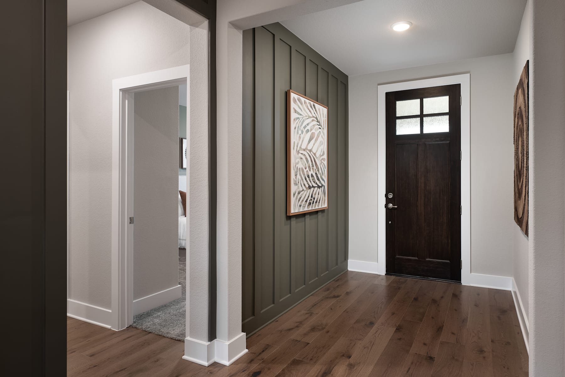 A modern and minimalist entryway with a dark wooden door, a gray accent wall, and a framed artwork hanging on the wall.