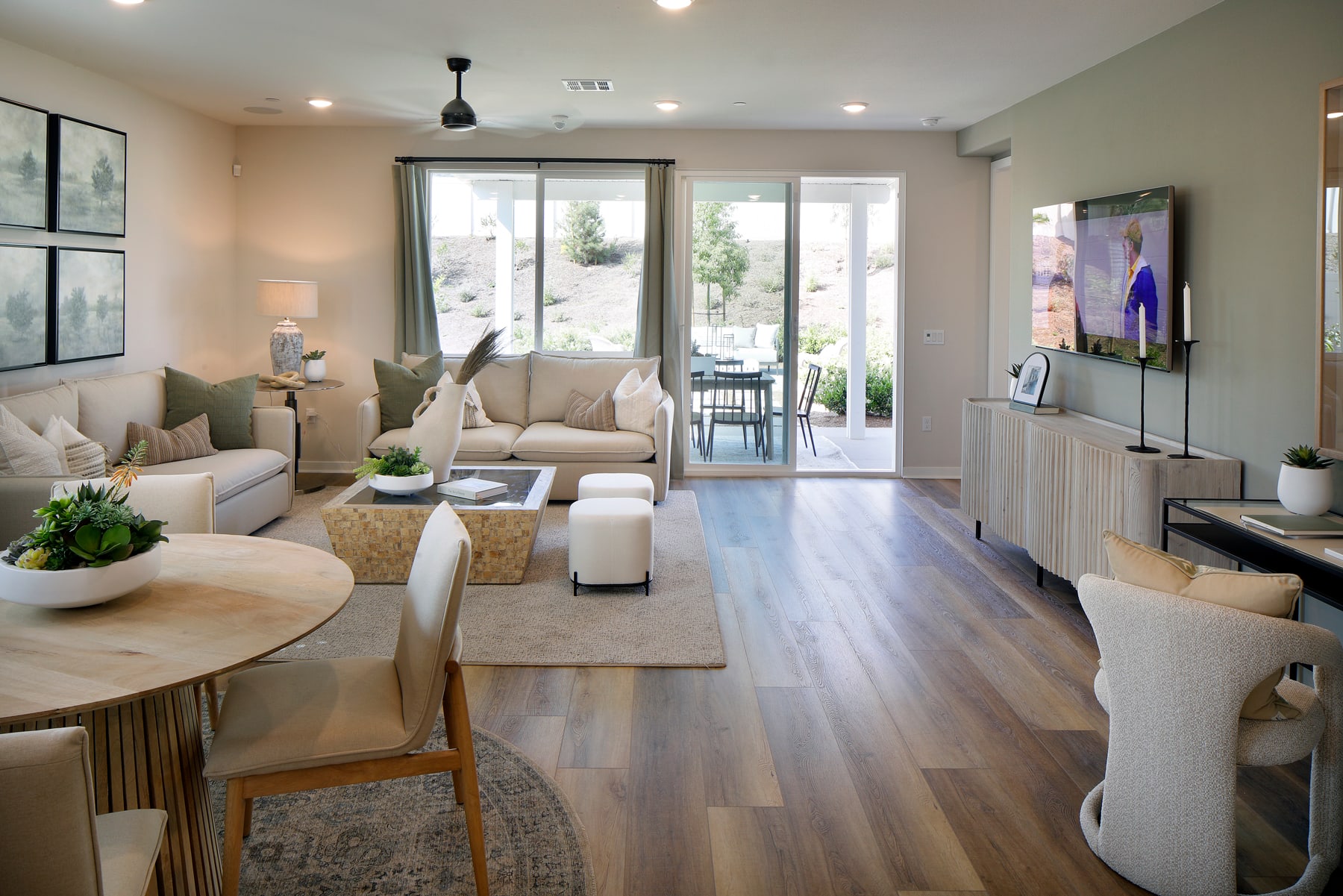 A cozy and inviting living room with a comfortable sofa, armchairs, and a dining area, featuring large windows that allow natural light to flood the space and provide a view of the outdoor surroundings.
