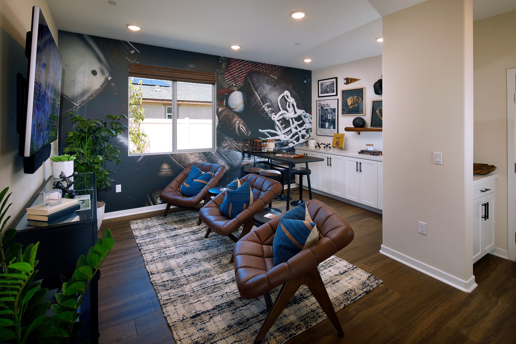 The image depicts a cozy and stylish home office space with comfortable leather chairs, a large wall mural, and various decorative elements such as plants and framed artwork.