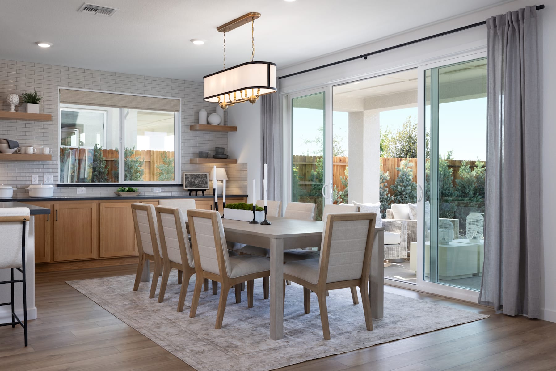 A modern and spacious dining room with a wooden table, upholstered chairs, and a large window overlooking a lush outdoor area.