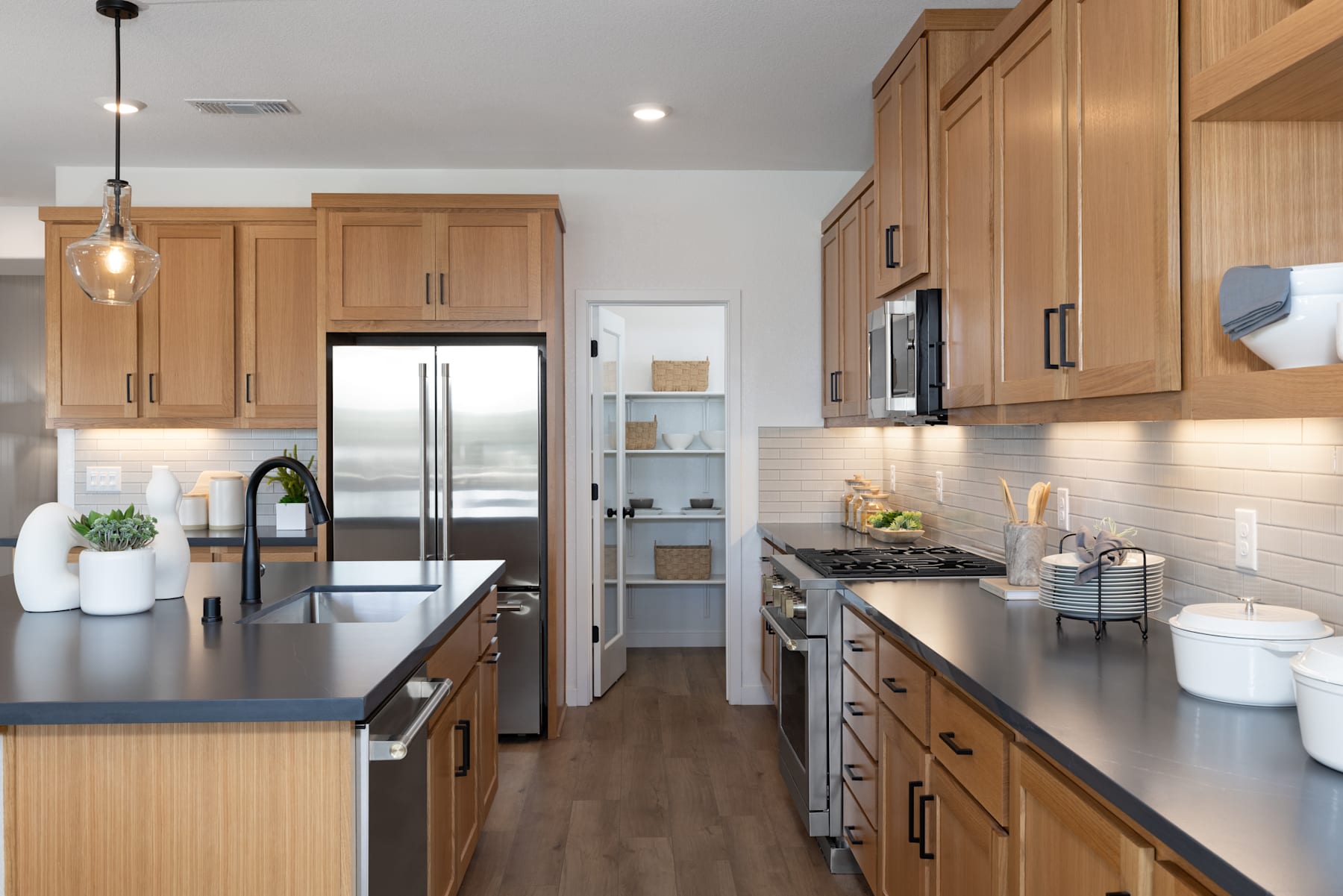 A modern and well-equipped kitchen with light wood cabinets, stainless steel appliances, and a sleek countertop, set against a neutral-toned backdrop.