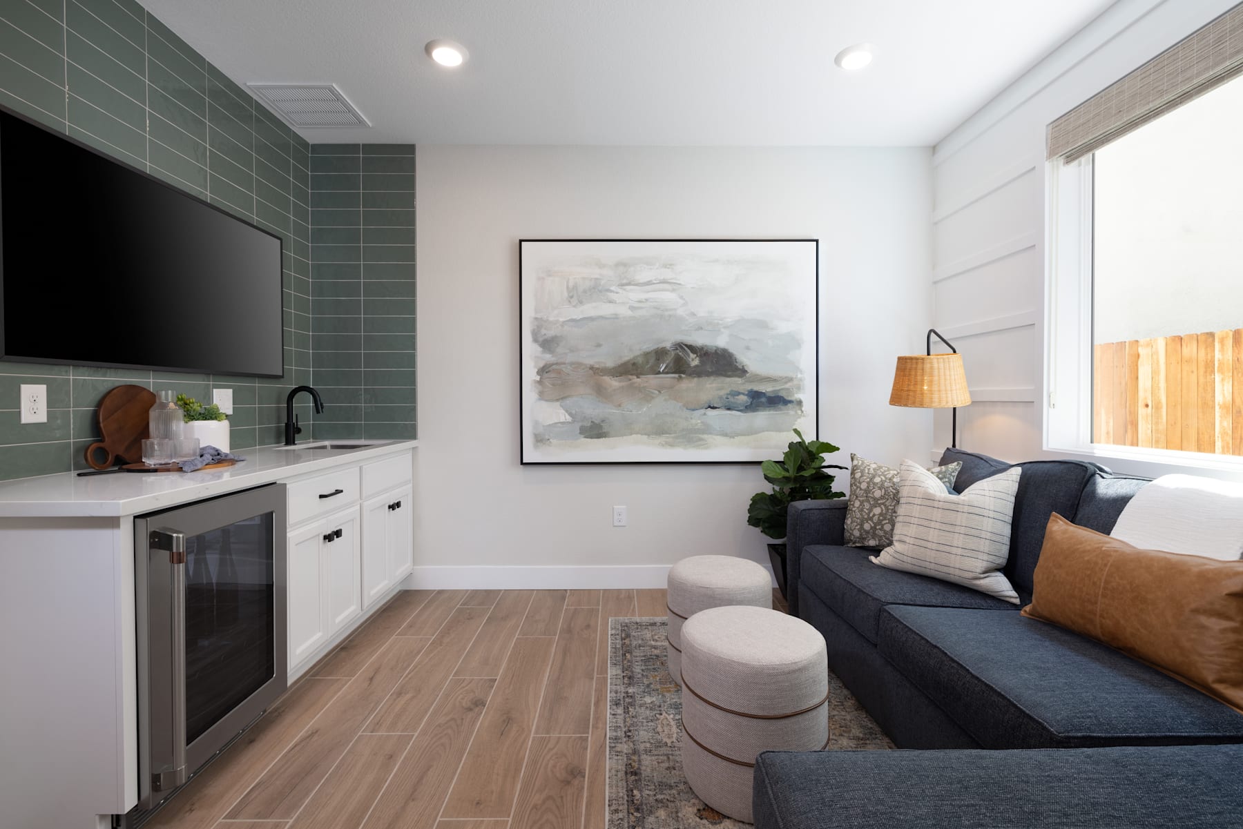 A modern and cozy living space with a kitchen area, a comfortable sofa, and a large abstract artwork on the wall.