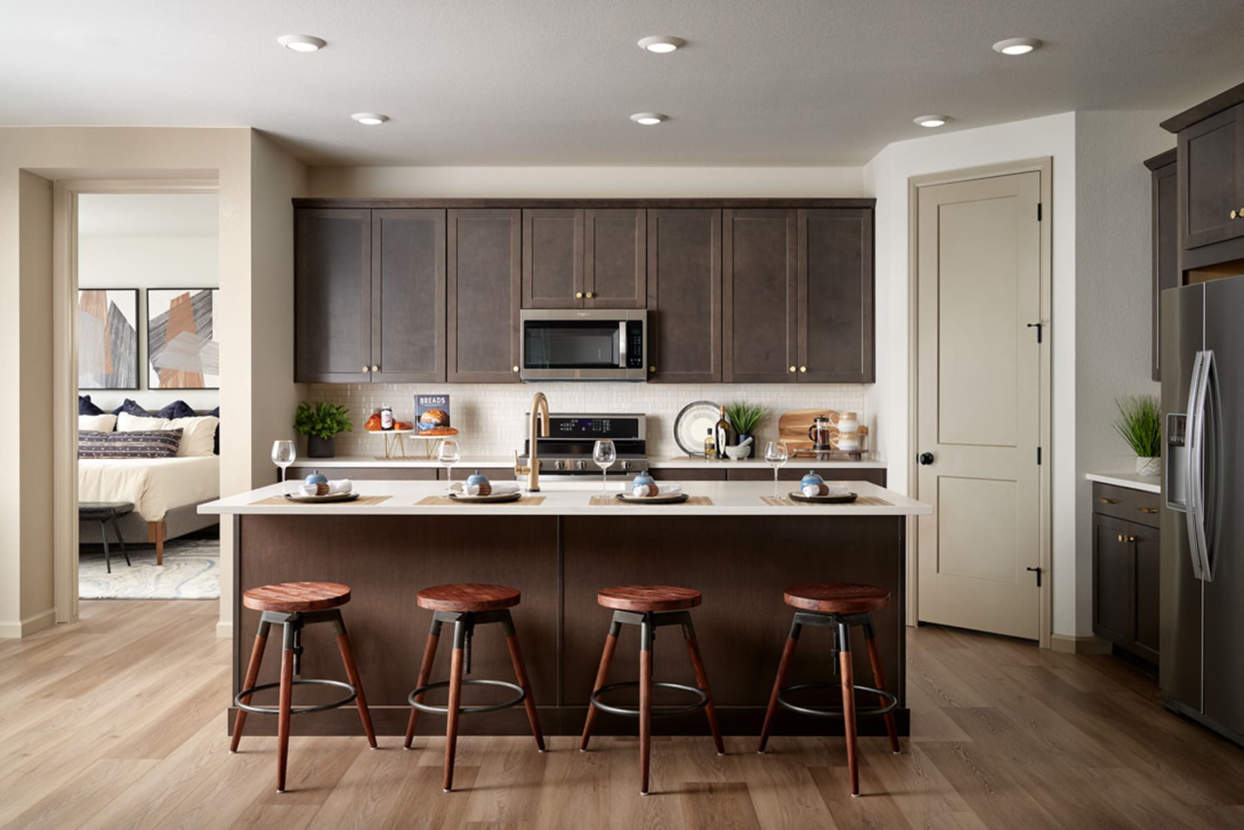 A modern and well-equipped kitchen with dark wood cabinets, a central island with bar stools, and various appliances and decor items arranged neatly throughout the space.