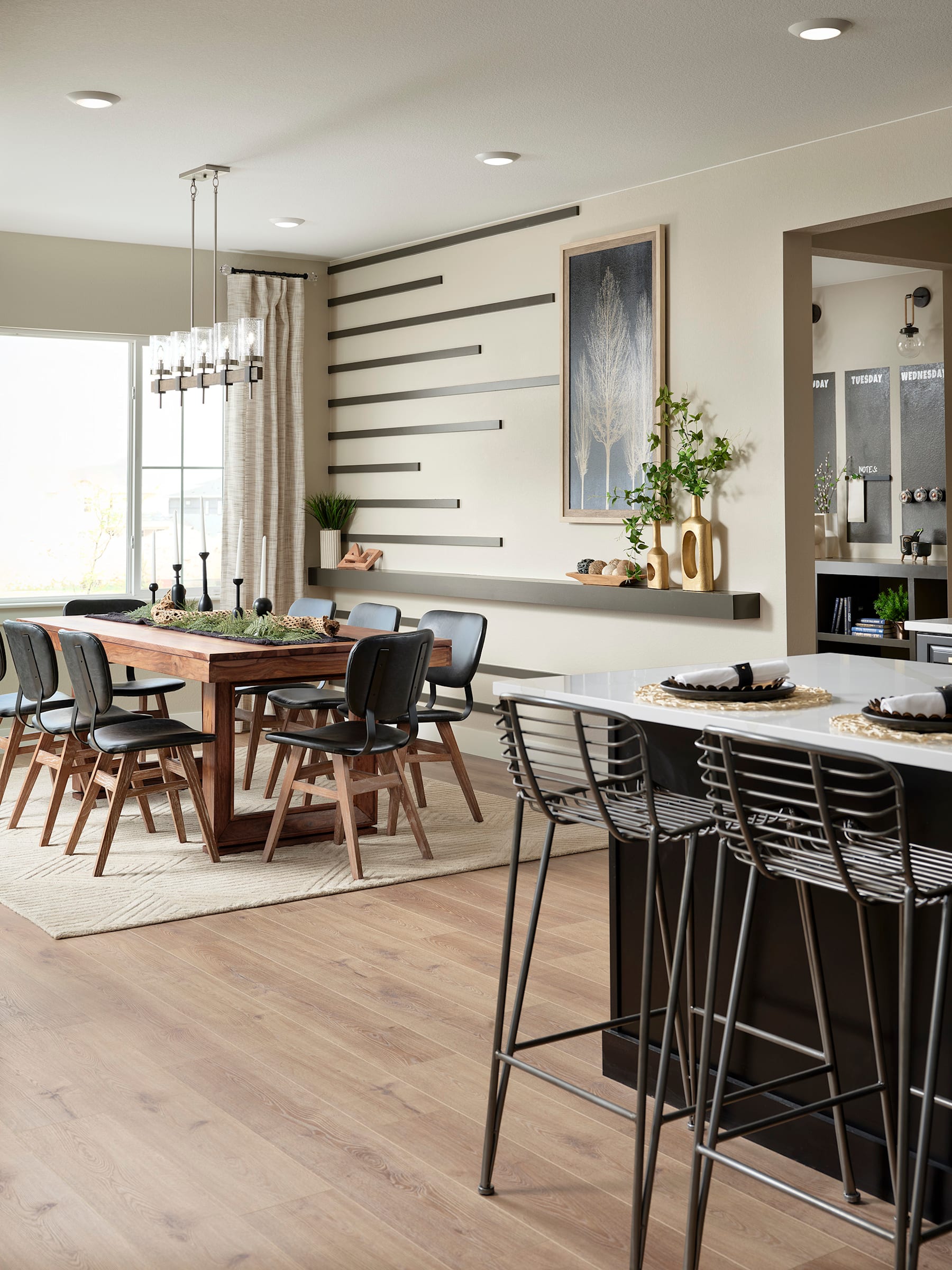 A modern and spacious open-plan kitchen and dining area with a wooden dining table, black chairs, and a kitchen island with bar stools.
