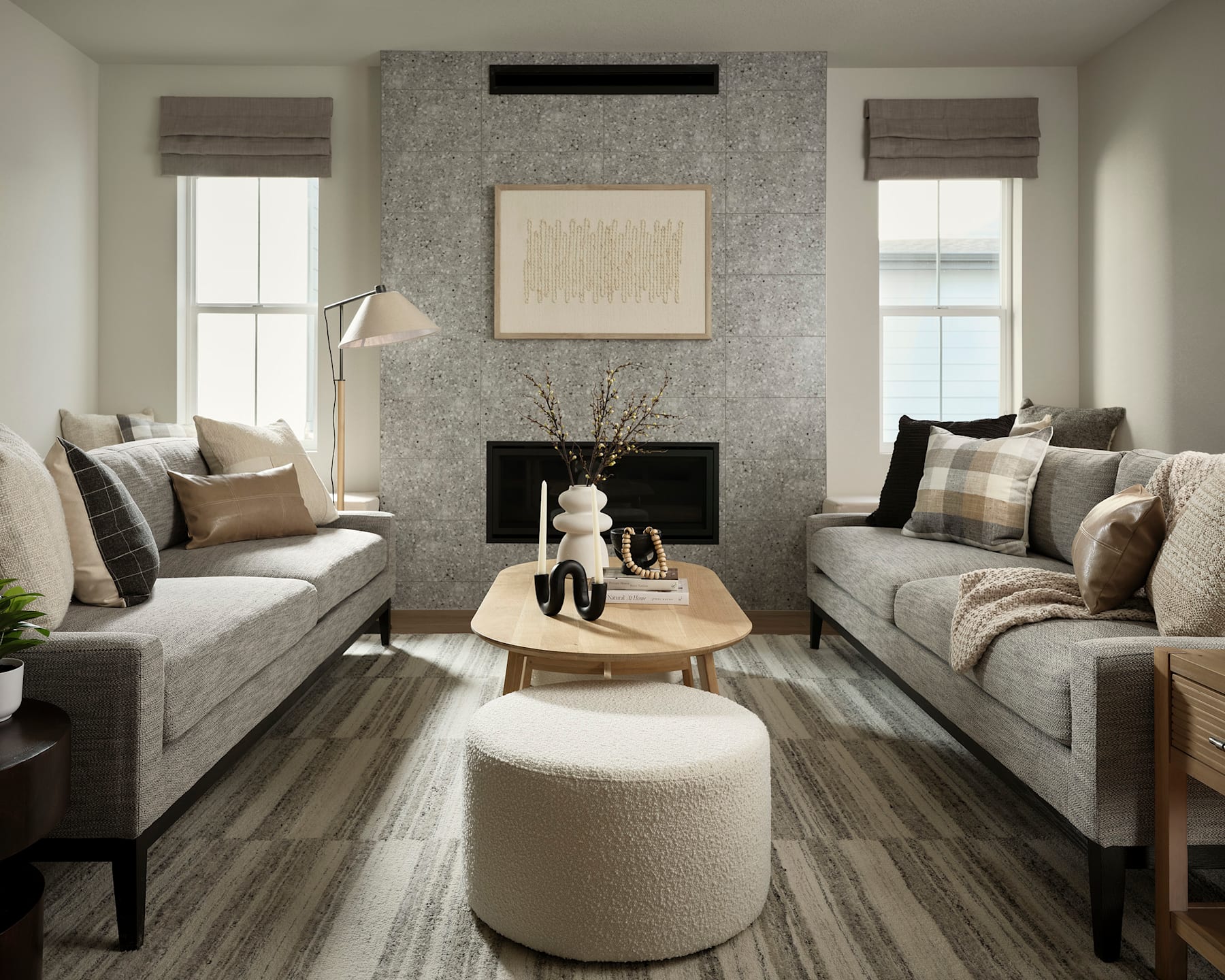 A cozy and inviting living room with plush gray sofas, a wooden coffee table, and a fireplace with a decorative frame on the wall, creating a warm and comfortable atmosphere.