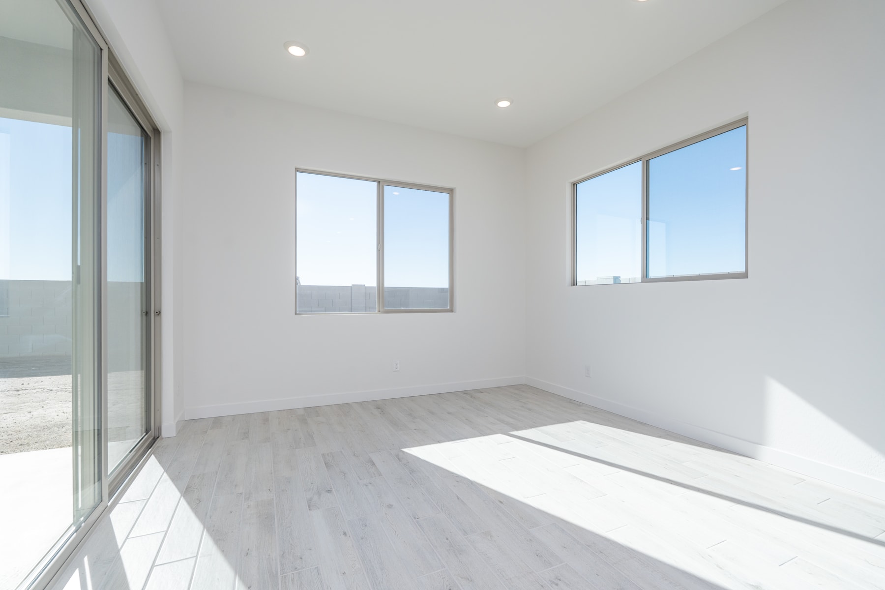 A bright, minimalist room with large windows, a hardwood floor, and a clean, uncluttered interior.
