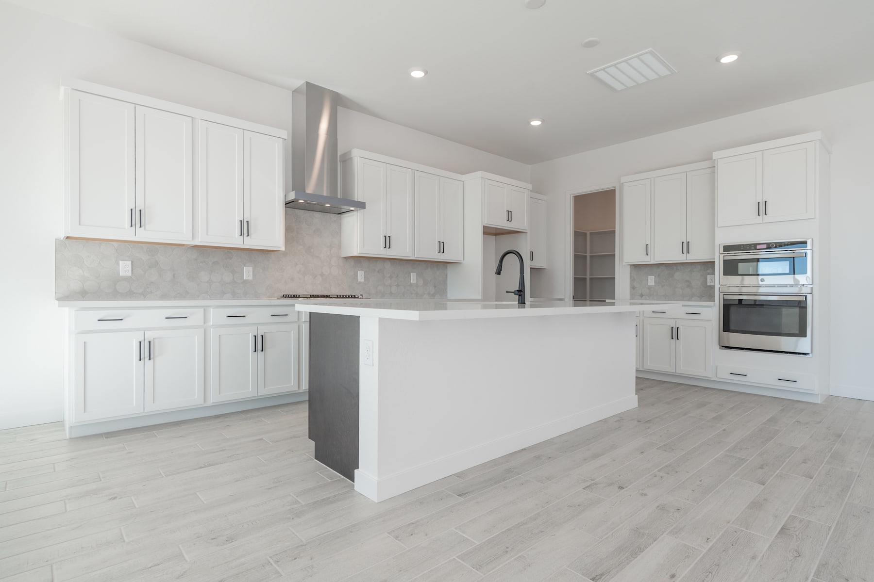 A modern, bright, and spacious kitchen with white cabinets, stainless steel appliances, and a central island with a sink.