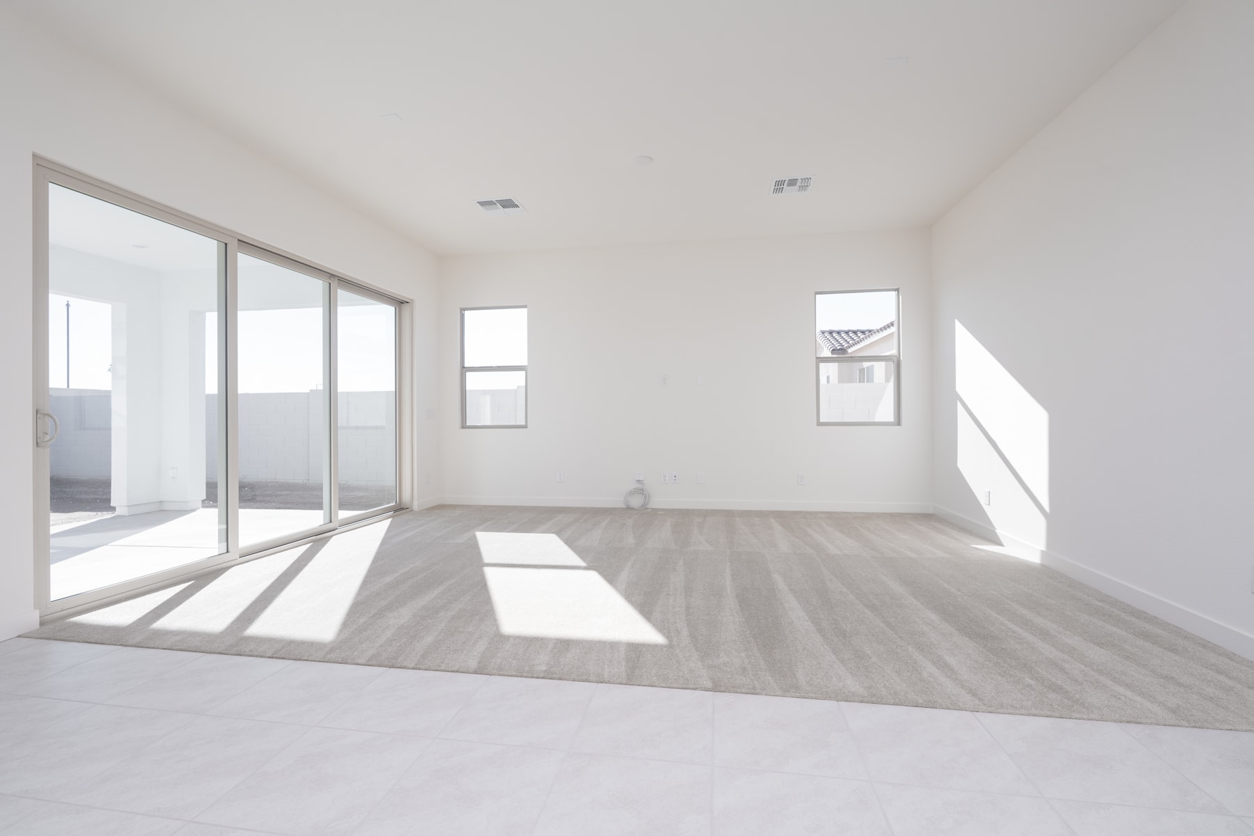 A spacious, minimalist room with large windows, a hardwood floor, and a clean, bright atmosphere.