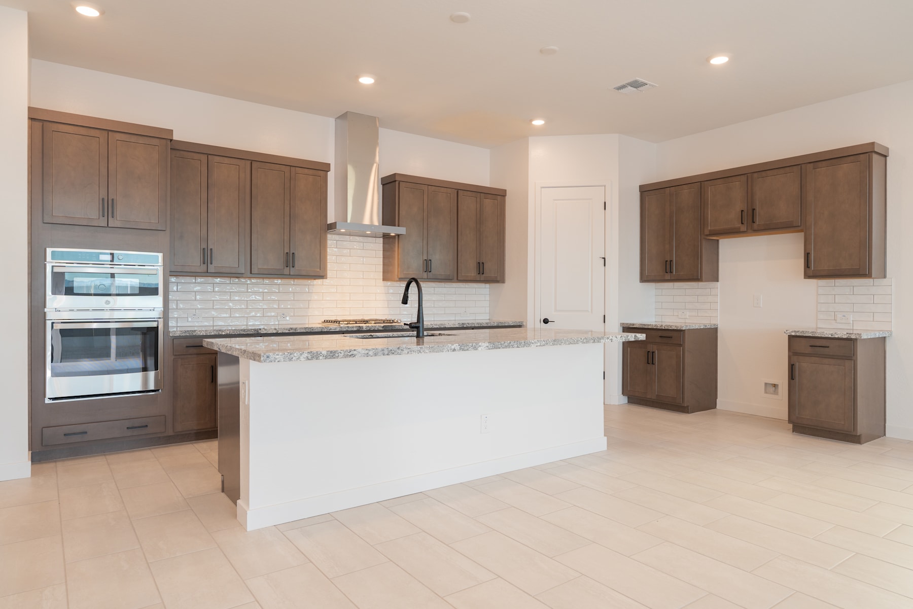 A modern, open-concept kitchen with dark wood cabinets, a white island, and a light-colored hardwood floor.