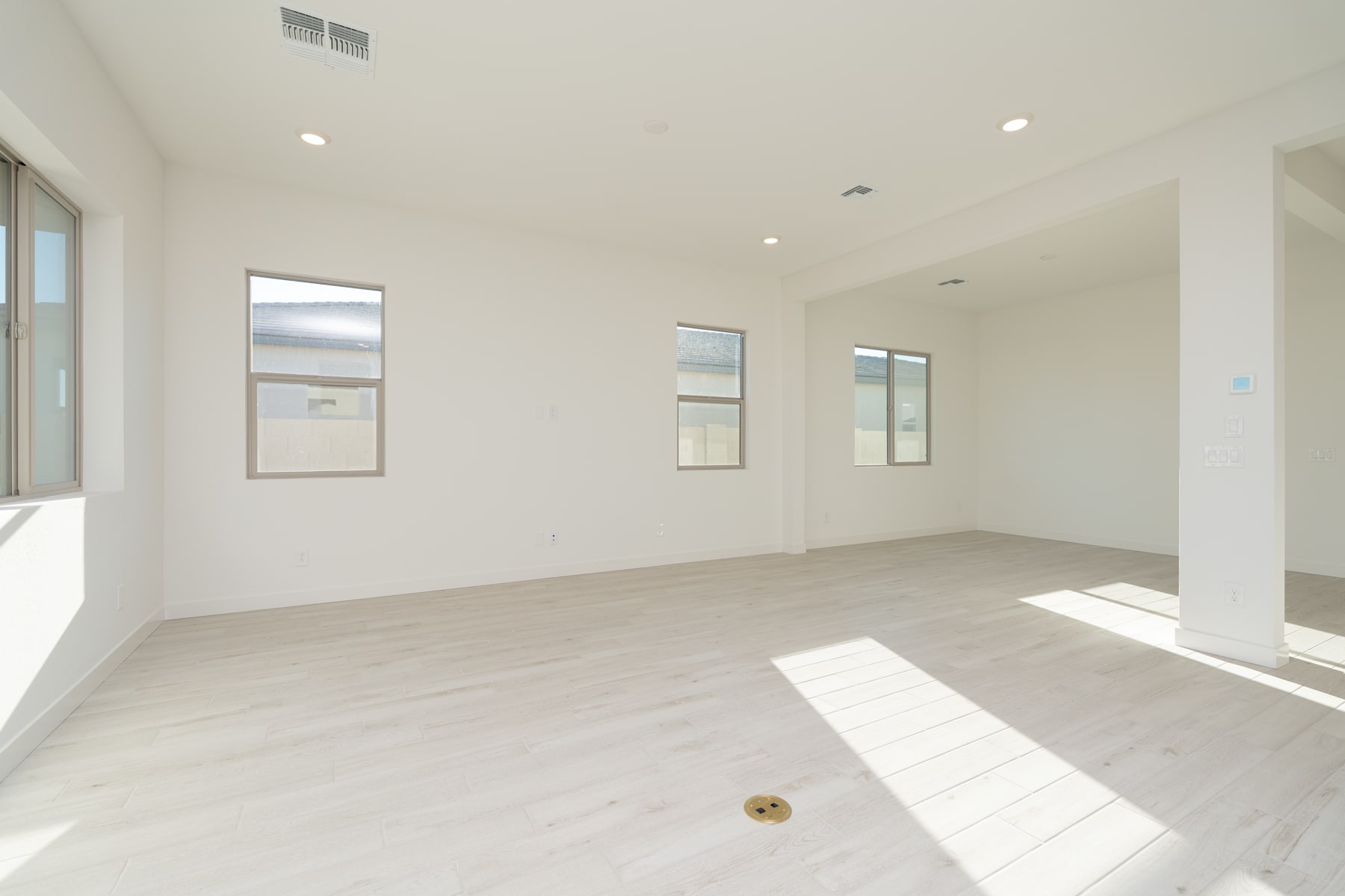 A bright and spacious room with white walls, hardwood floors, and large windows allowing natural light to flood the space.