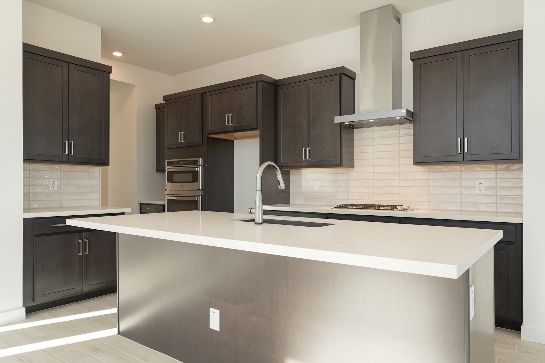 A modern, well-equipped kitchen with dark wood cabinets, a white countertop, and stainless steel appliances.