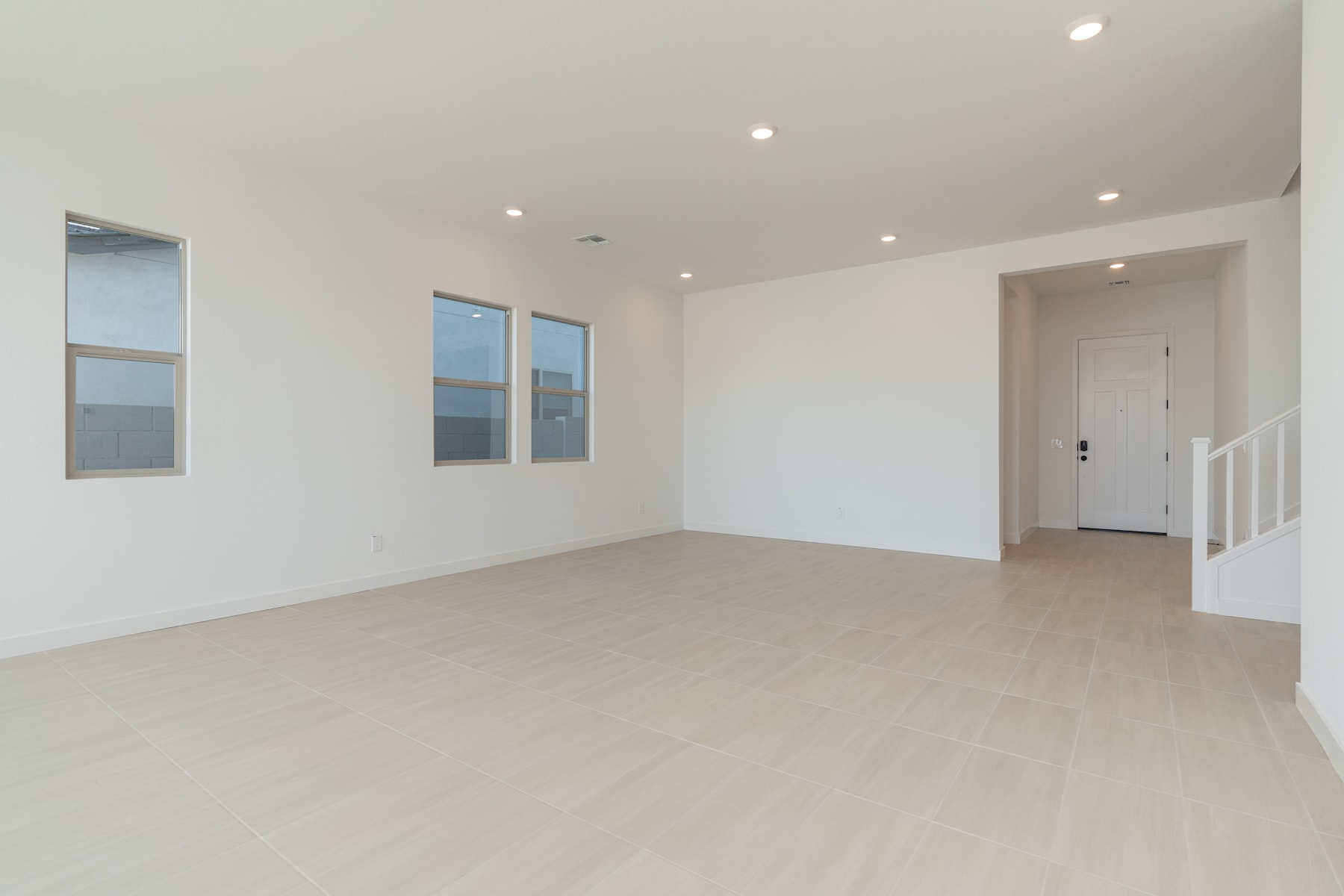 A spacious, minimalist room with white walls, hardwood floors, and recessed lighting, providing a clean and bright atmosphere.