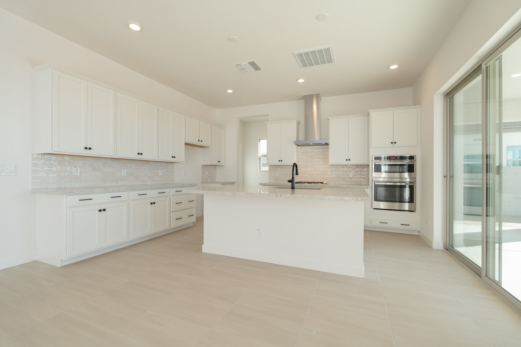 A spacious, modern kitchen with white cabinets, stainless steel appliances, and a large window providing natural light.