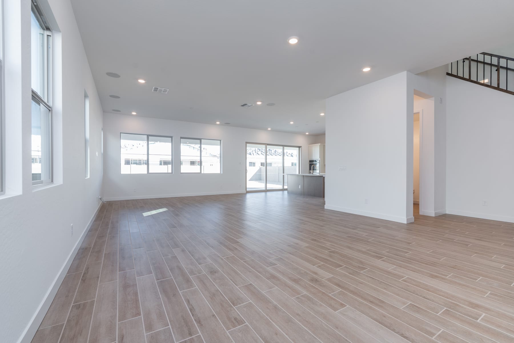 A spacious, well-lit room with a hardwood floor and large windows, creating a bright and airy atmosphere.
