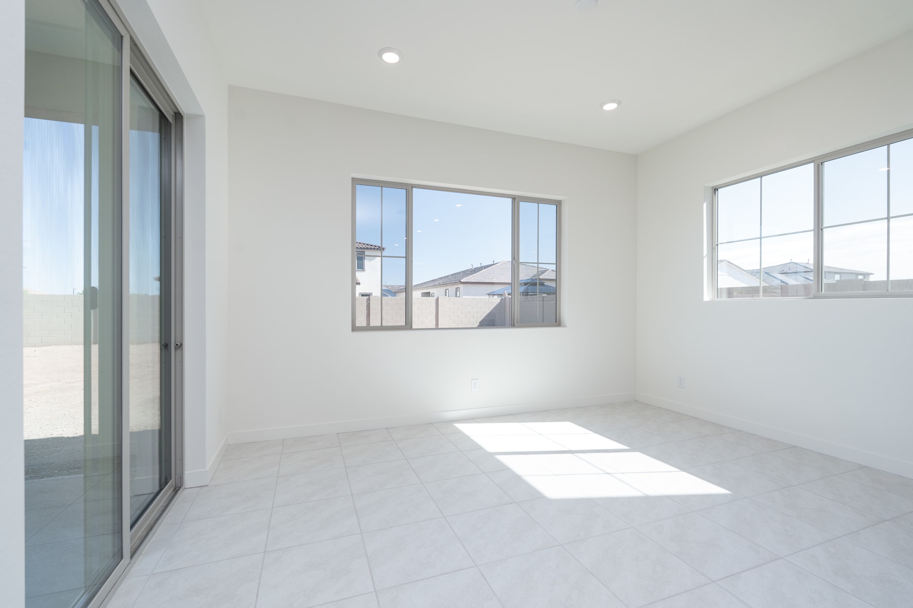 A bright, spacious room with large windows, white walls, and a tiled floor. The room appears to be part of a modern, minimalist interior design.