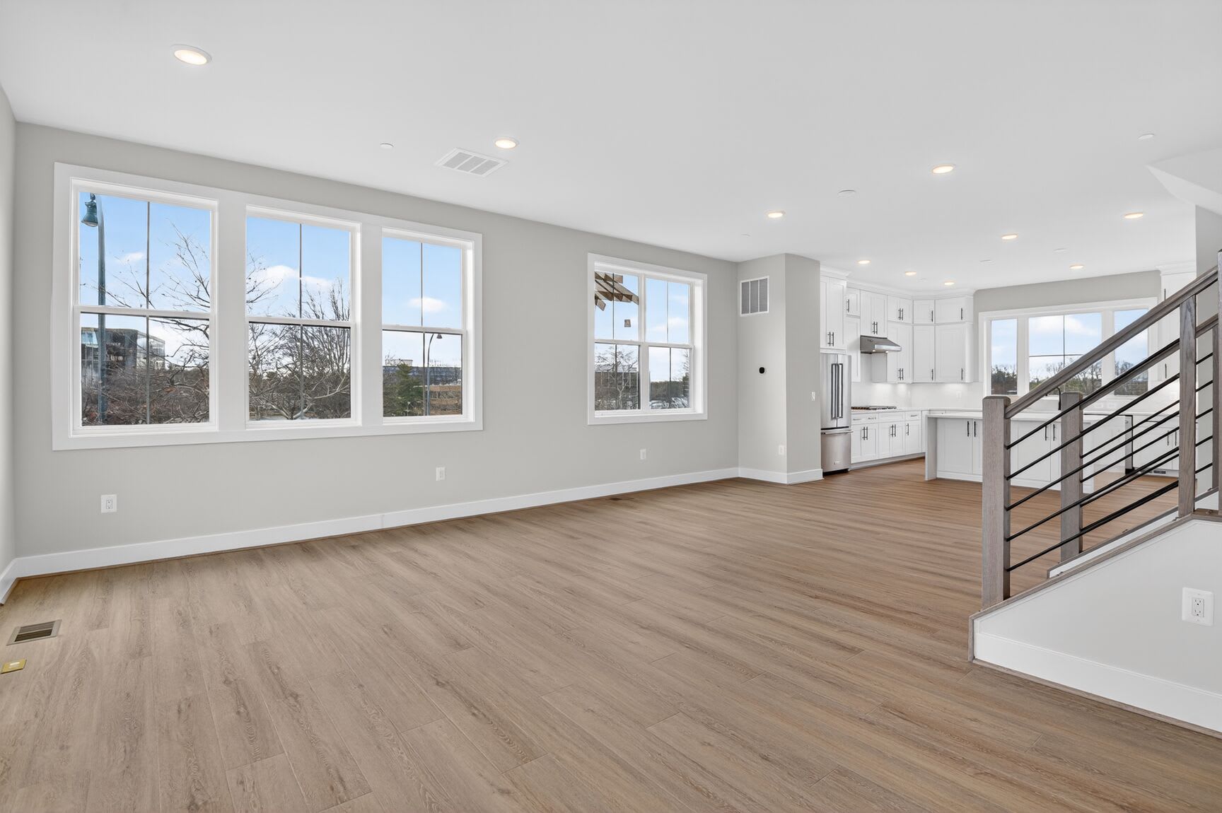 A spacious, modern living room with large windows, hardwood floors, and a minimalist design.
