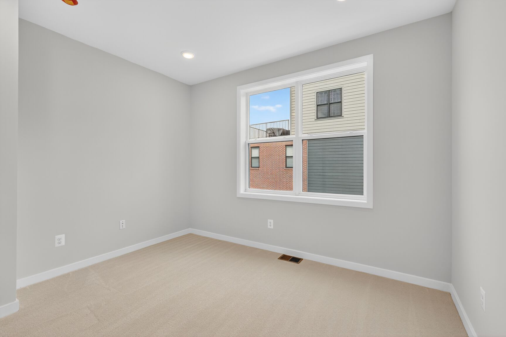 A spacious, well-lit room with a large window, hardwood floors, and neutral-colored walls.