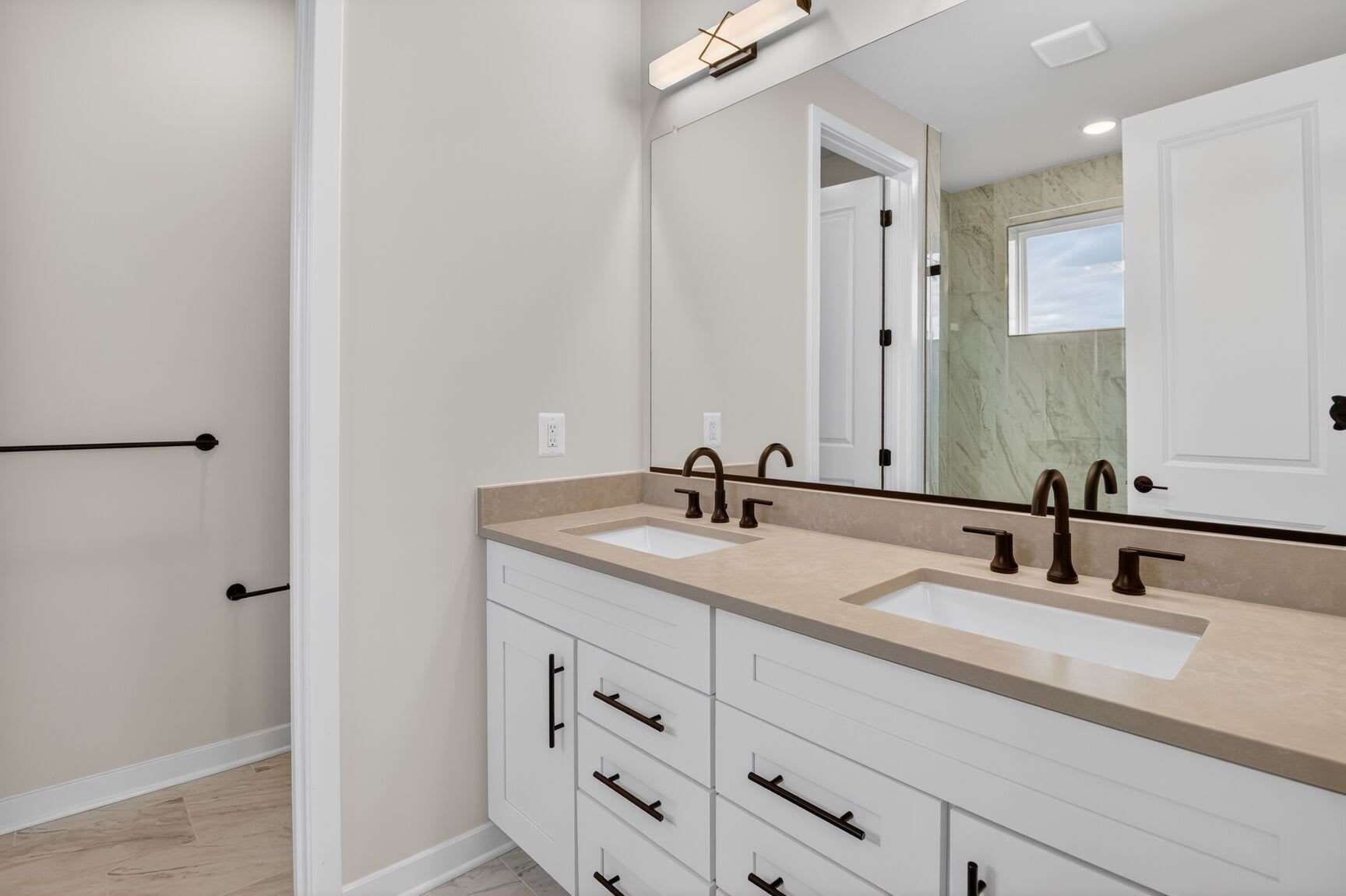 A modern and well-designed bathroom with a double vanity, white cabinets, and a large mirror on the wall.