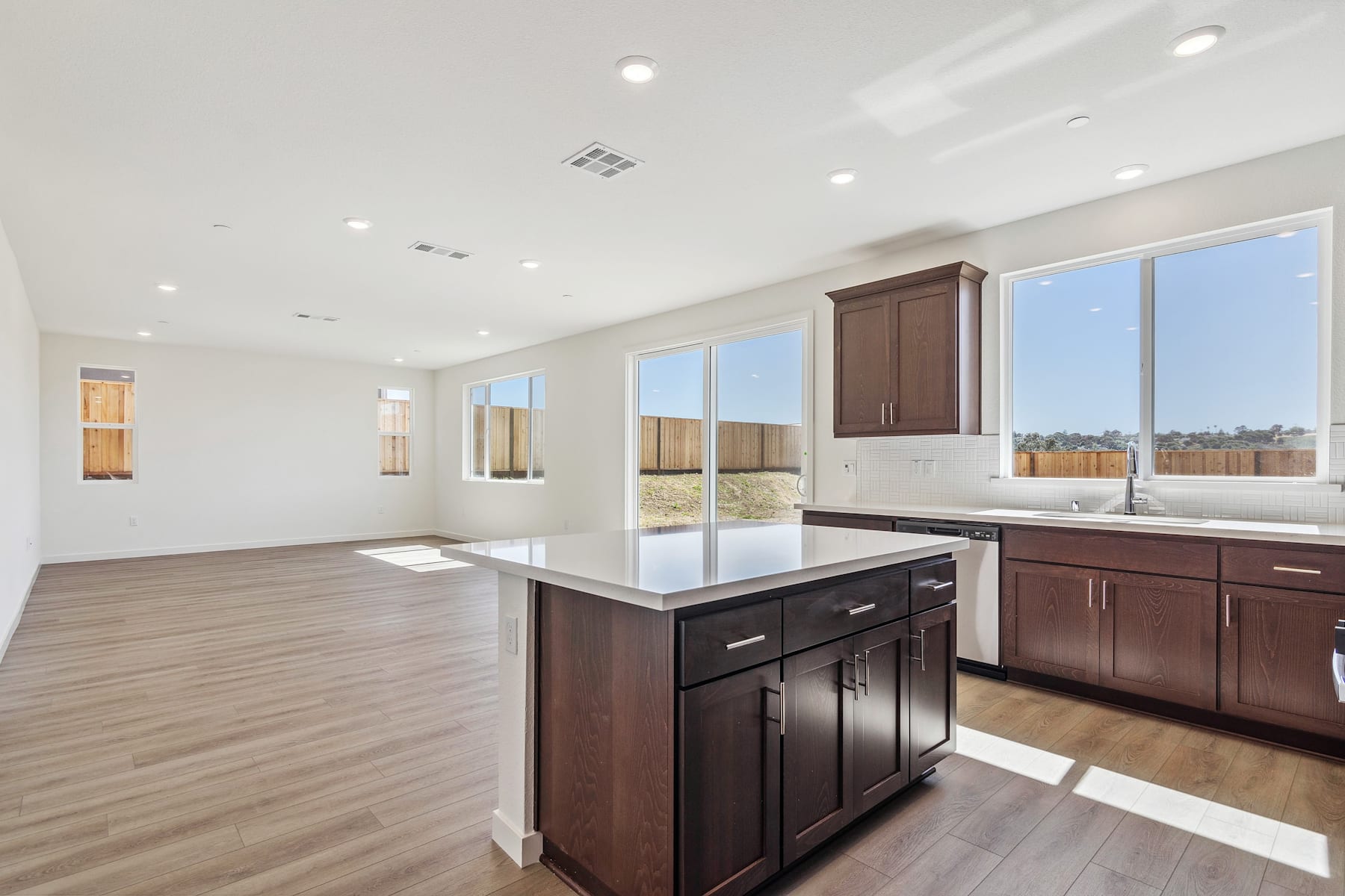 A spacious and modern kitchen with dark wood cabinets, a central island, and large windows providing ample natural light.