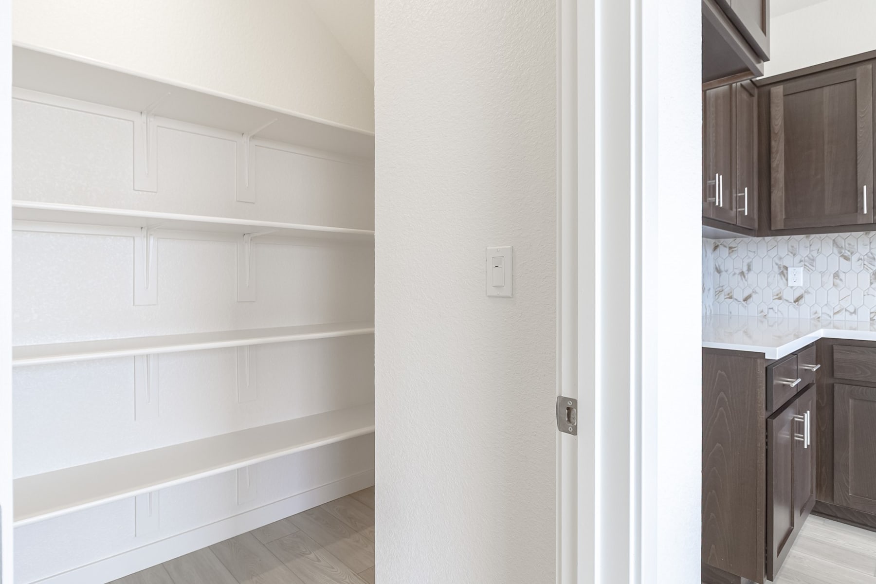 A well-lit, modern kitchen with white shelves and dark cabinets, showcasing a clean and organized interior design.
