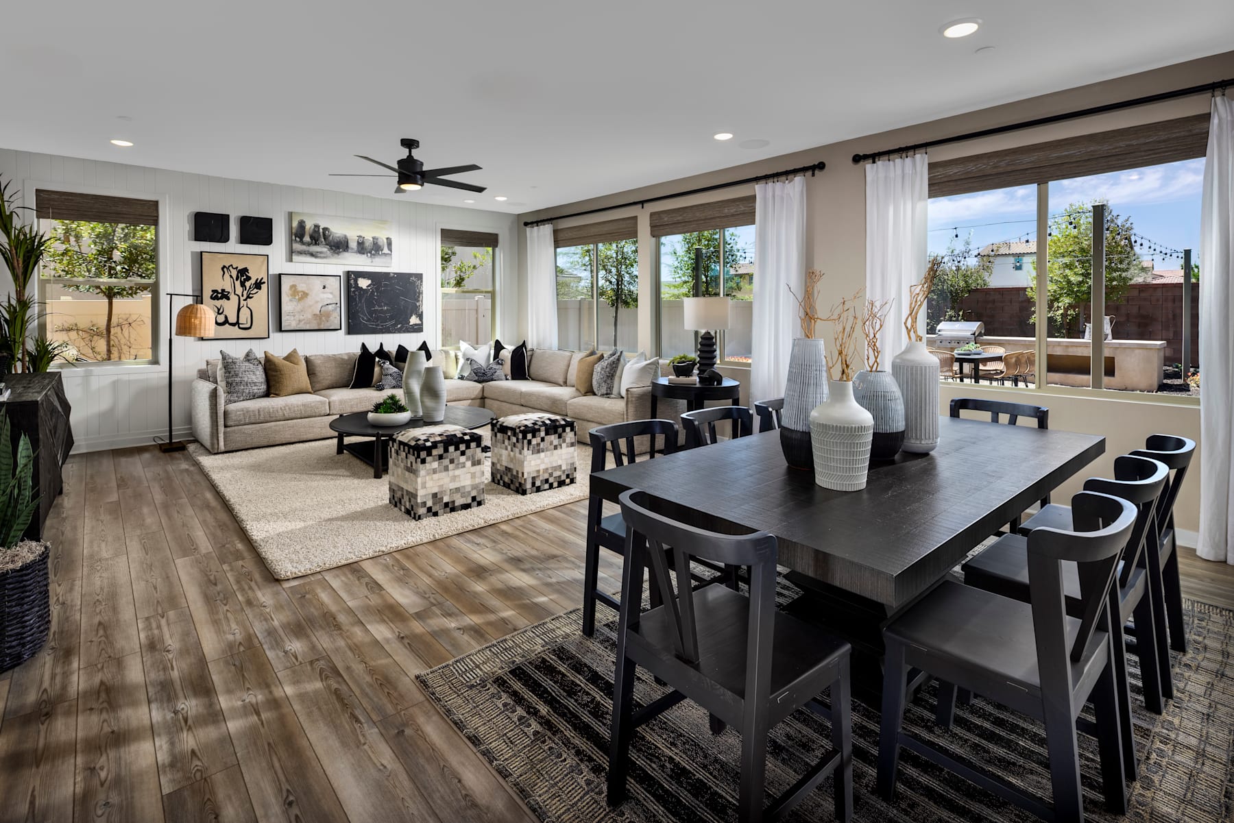 A spacious and modern living room with a dining area, featuring a large sofa, a wooden dining table with chairs, and various decorative elements throughout the space.