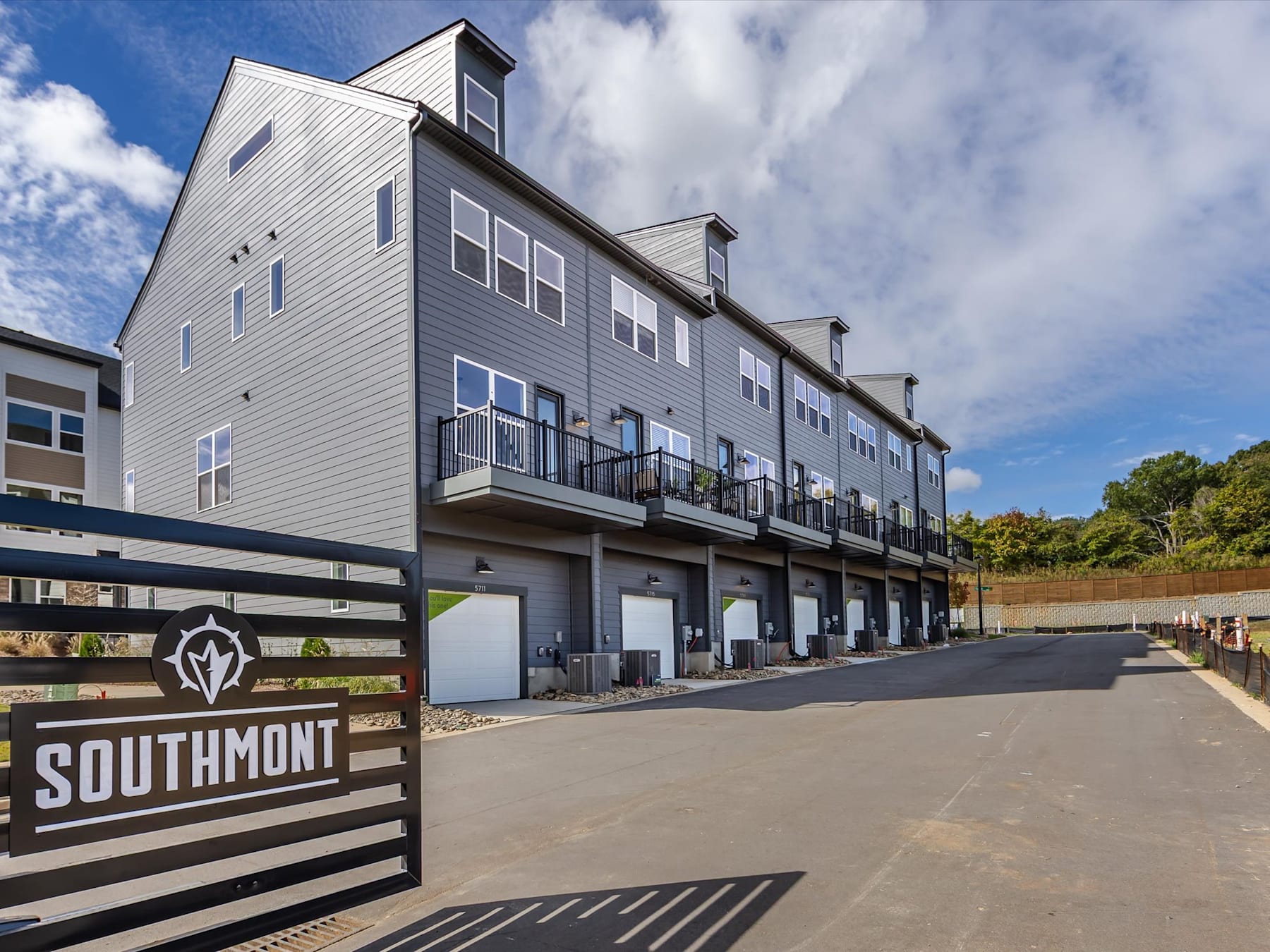 A multi-story residential building with a prominent sign reading "Southmont" in the foreground, set against a backdrop of a blue sky with scattered clouds.