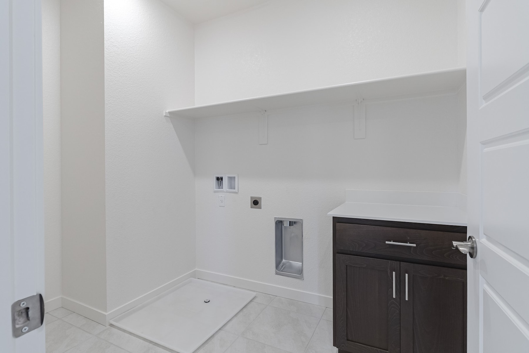 A modern, minimalist bathroom interior with a dark-colored vanity cabinet and a recessed wall niche.