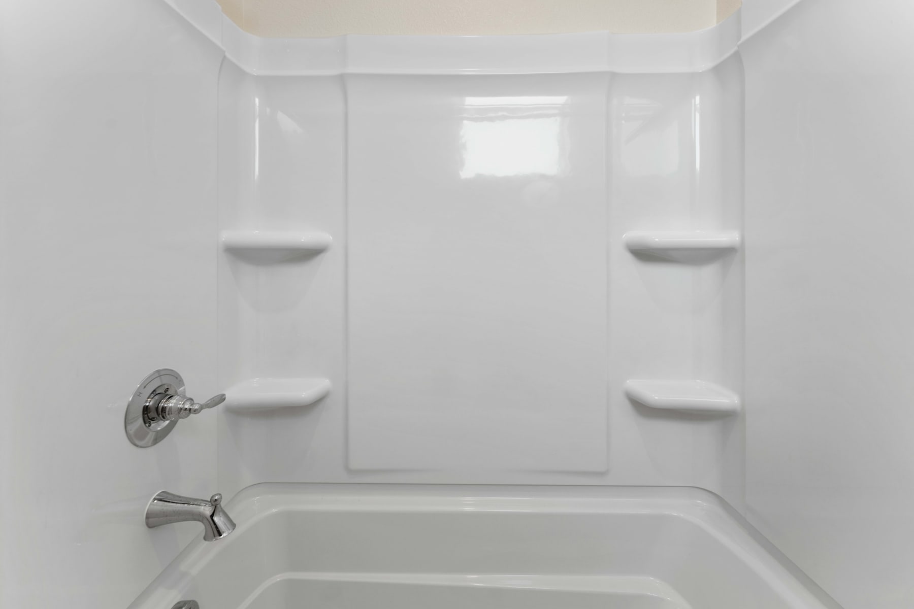 A bright, minimalist bathroom with a white tub and shower enclosure, and a simple, clean design.