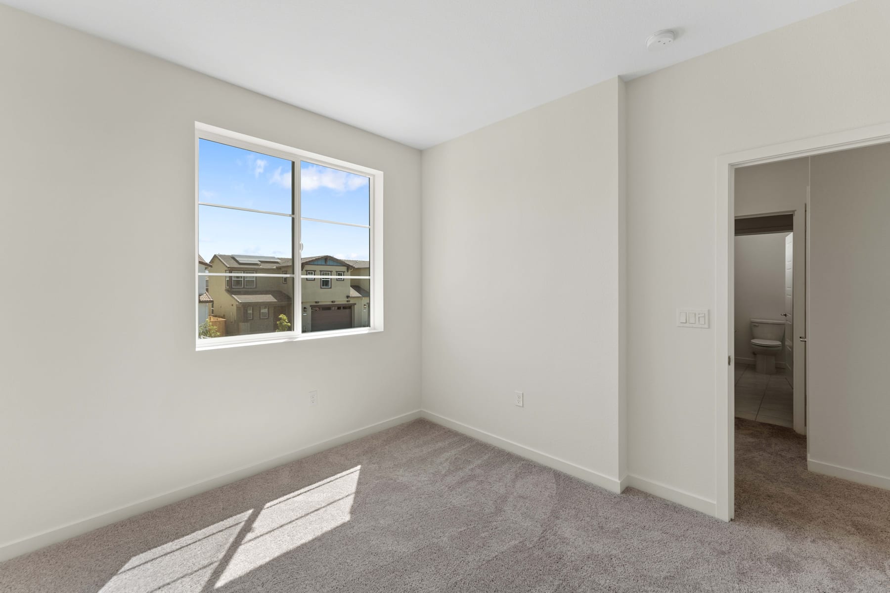 A spacious, well-lit room with a large window overlooking a scenic outdoor view, featuring a neutral color palette and clean, minimalist design.