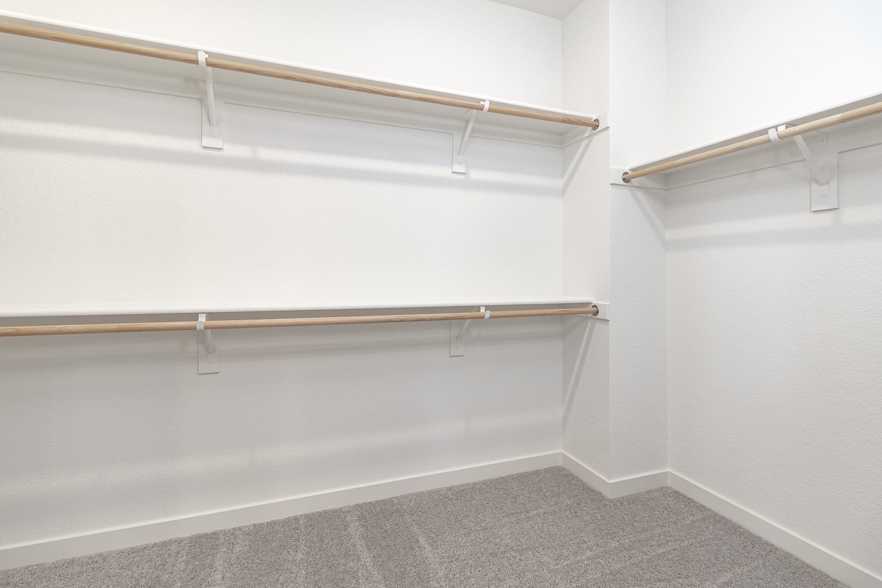 A spacious, well-lit closet with multiple shelves and hanging rods, providing ample storage space.