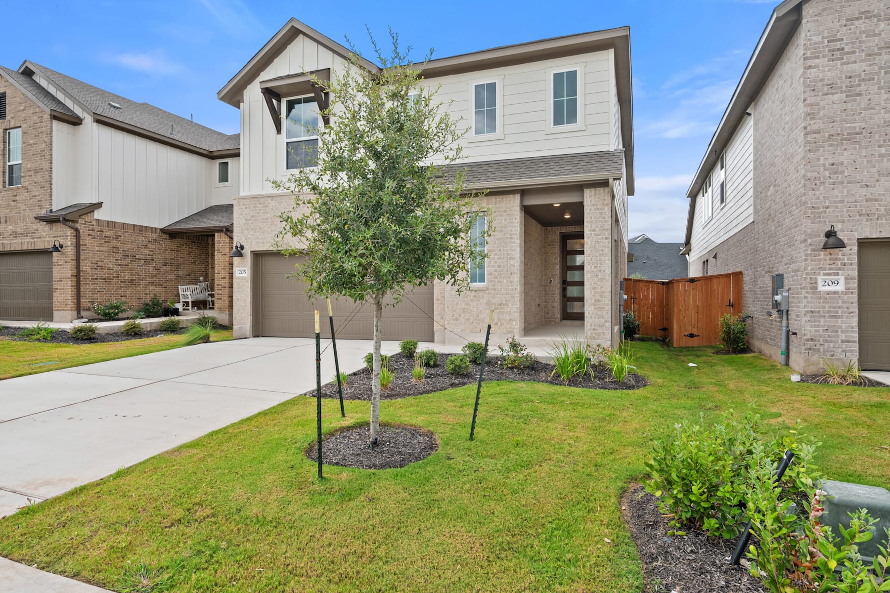 A two-story residential house with a well-maintained lawn, surrounded by other similar houses in a suburban neighborhood.