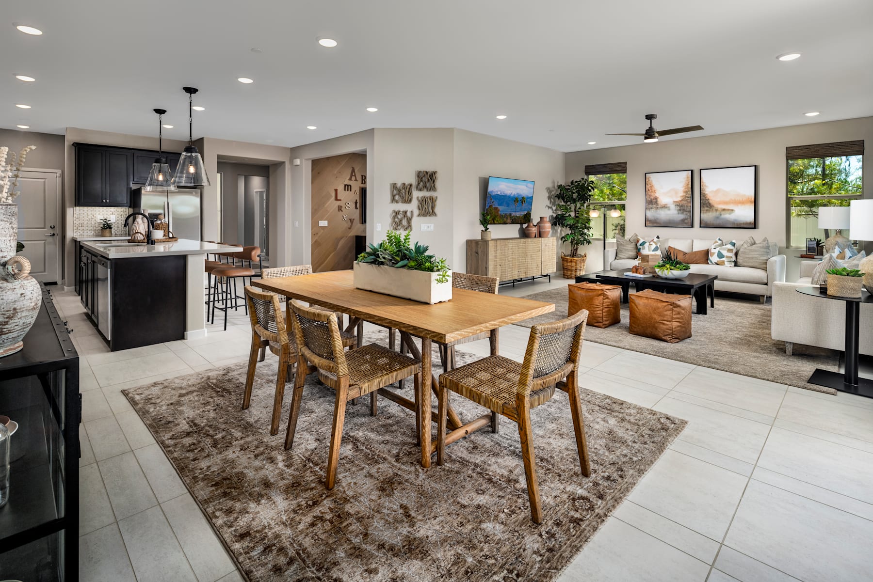 A spacious and well-designed open-concept living space with a dining area, kitchen, and living room, featuring a mix of modern and rustic elements, including a wooden dining table, pendant lighting, and artwork on the walls.