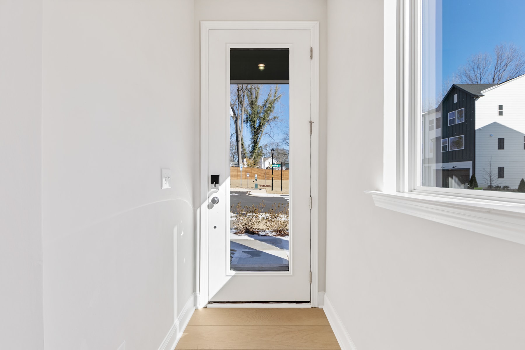 A bright, airy hallway with a white door leading to a snowy outdoor scene, creating a contrast between the indoor and outdoor environments.