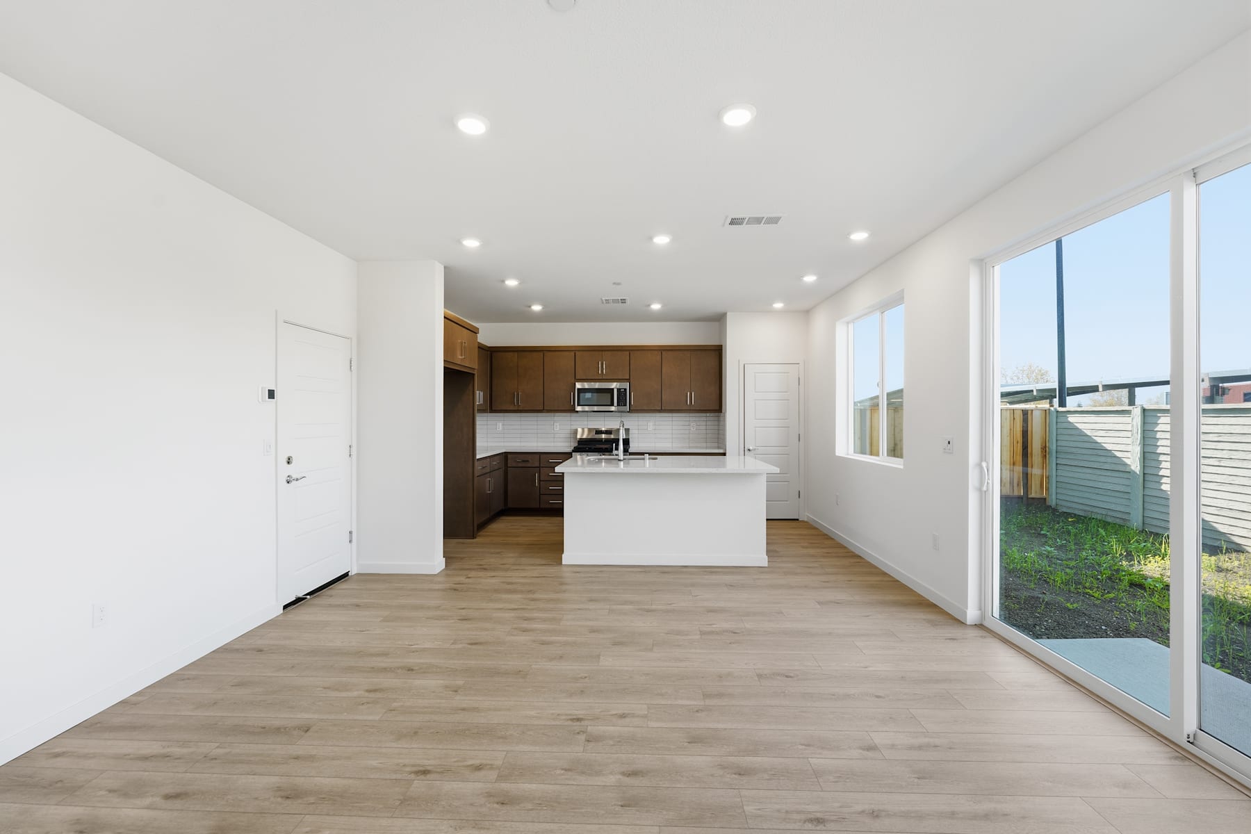 A spacious and modern open-plan living area with a kitchen, hardwood flooring, and large windows providing ample natural light.