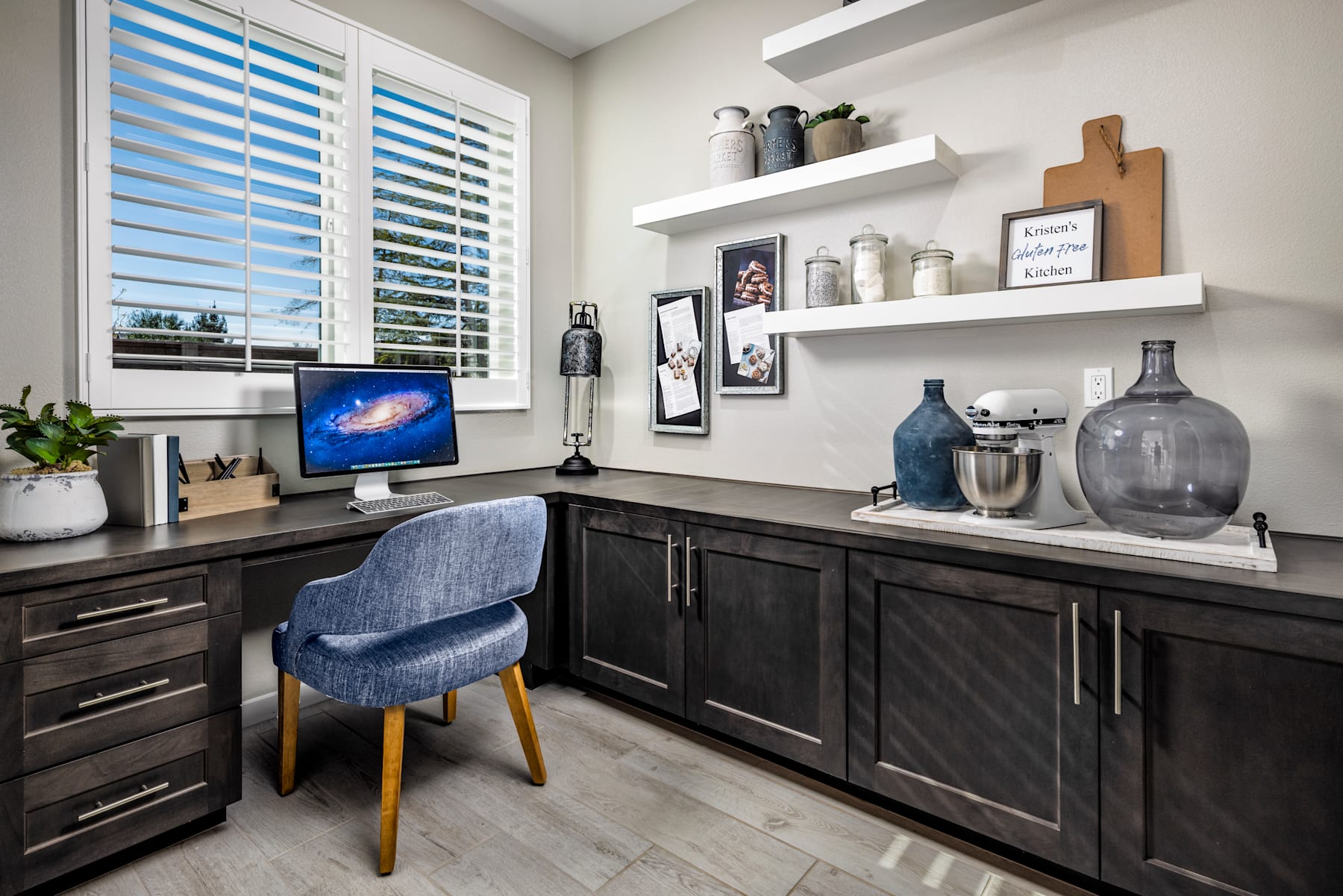A cozy and well-organized home office space with dark wood cabinets, shelves displaying decorative items, and a computer monitor on the desk.