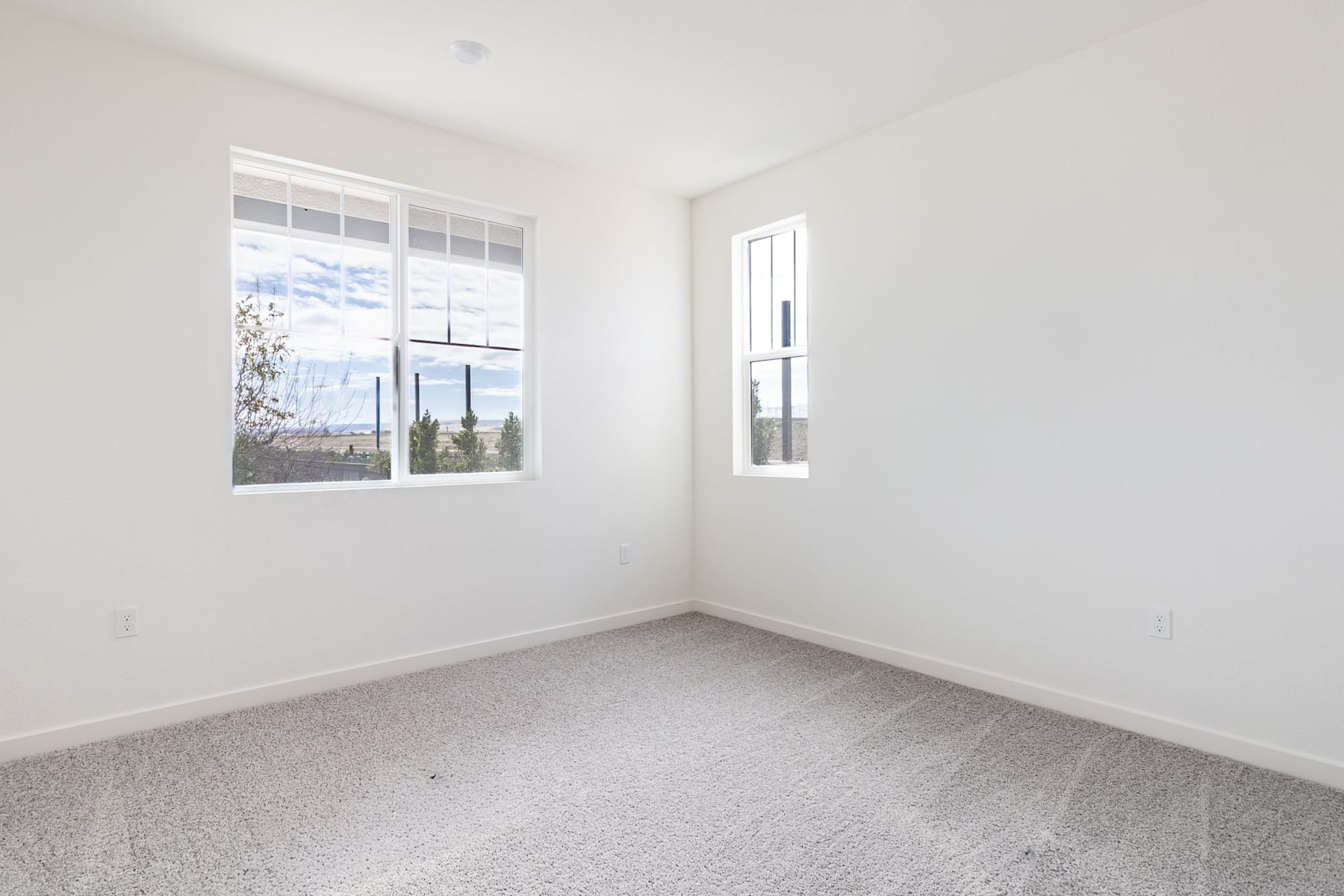 A bright, empty room with white walls, a large window, and a tiled floor.