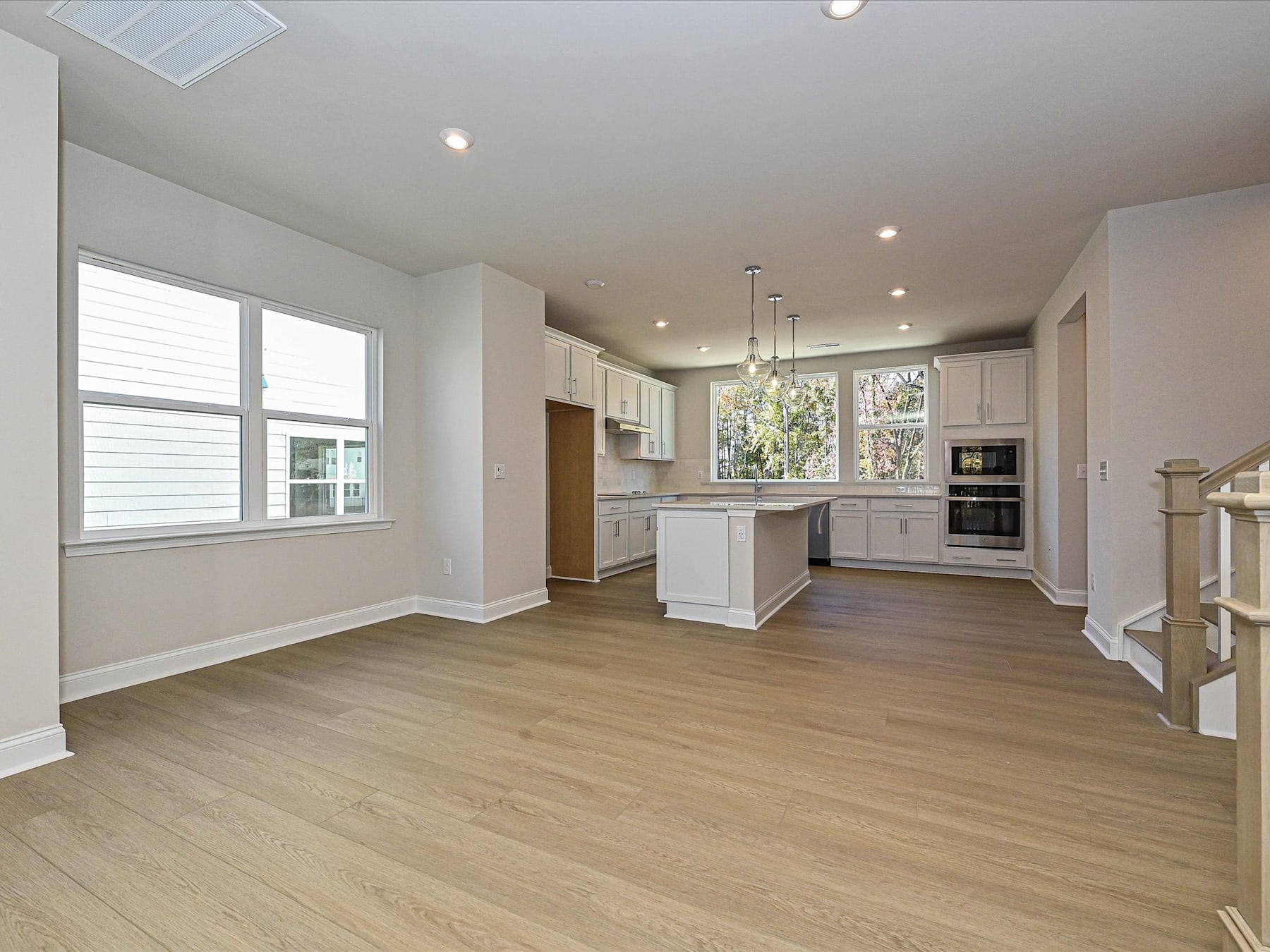 A spacious and modern kitchen with white cabinets, hardwood floors, and large windows that let in natural light.