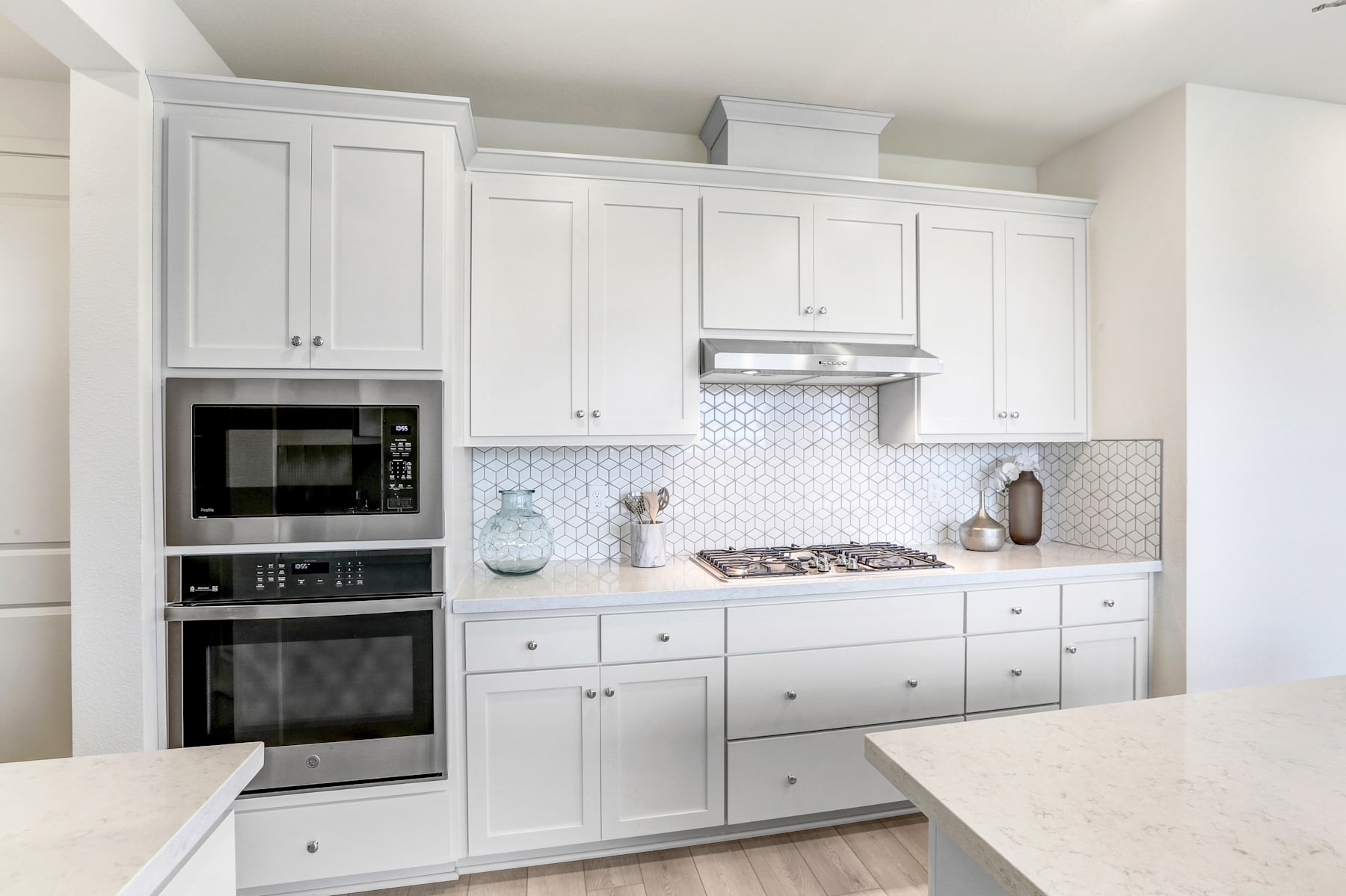 A modern, white kitchen with sleek cabinets, stainless steel appliances, and a tiled backsplash.