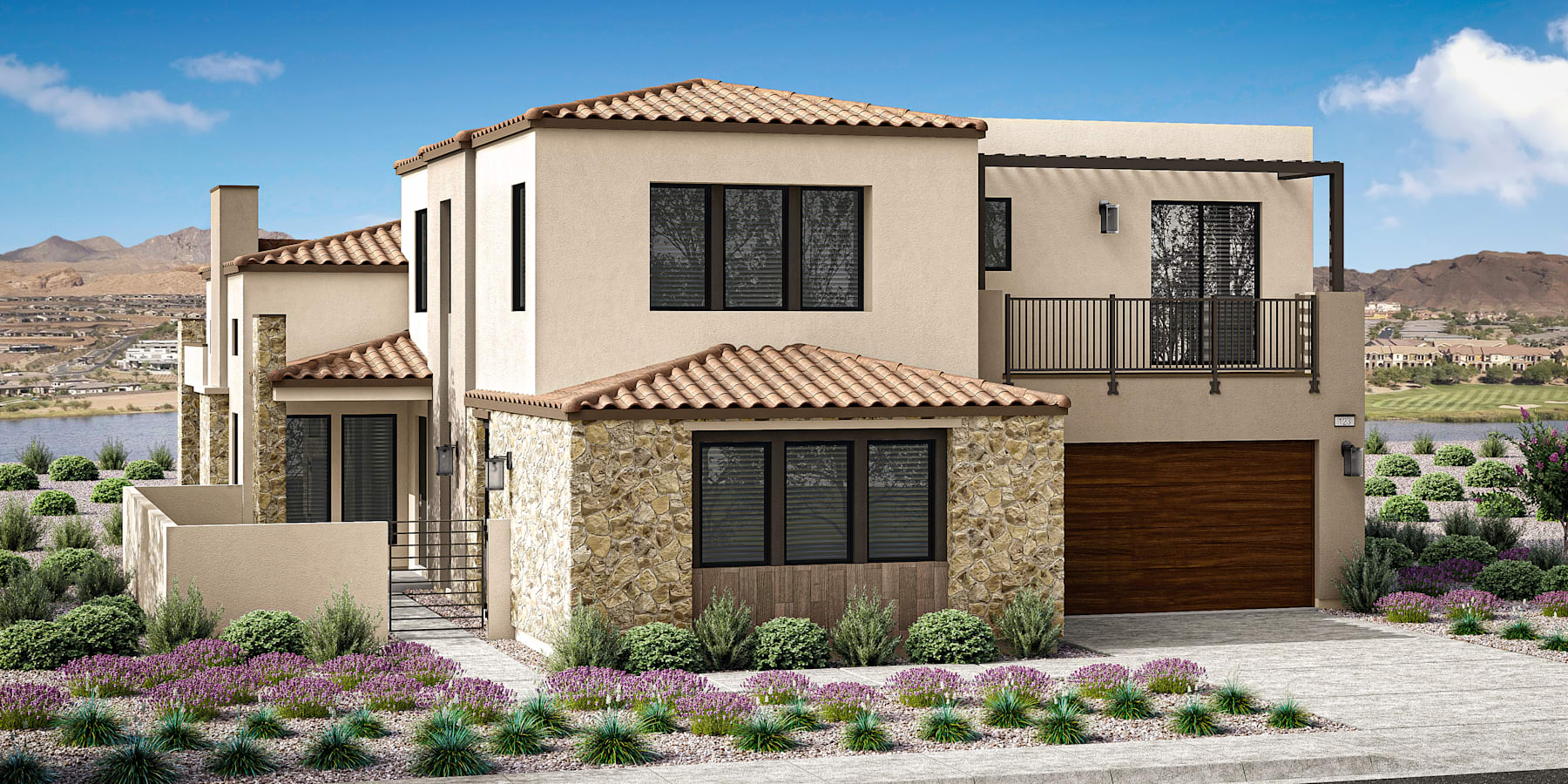 A two-story Mediterranean-style house with a tiled roof, stone exterior, and a landscaped front yard featuring colorful flowering plants against a backdrop of mountains and a clear blue sky.