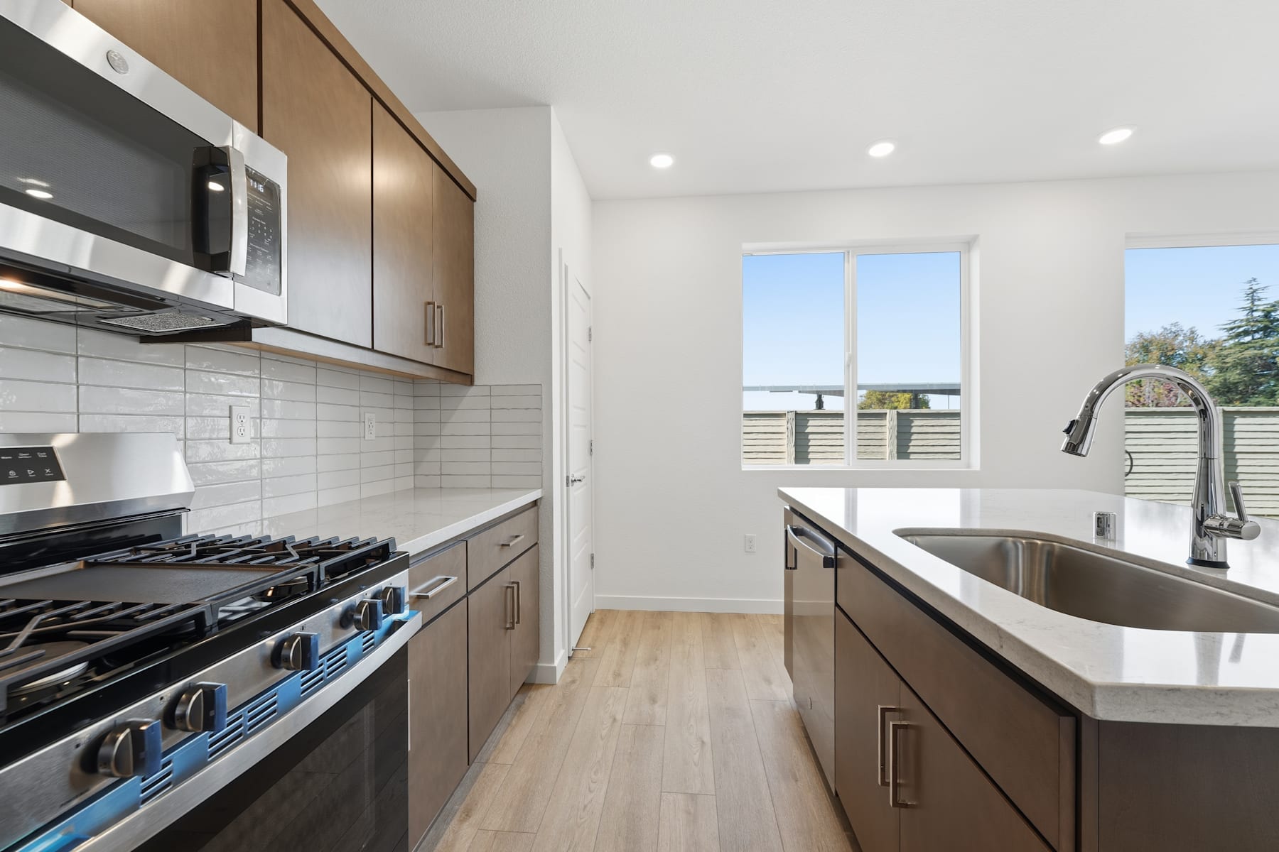 A modern, well-equipped kitchen with sleek cabinetry, stainless steel appliances, and a large window providing natural light and a view of the exterior.