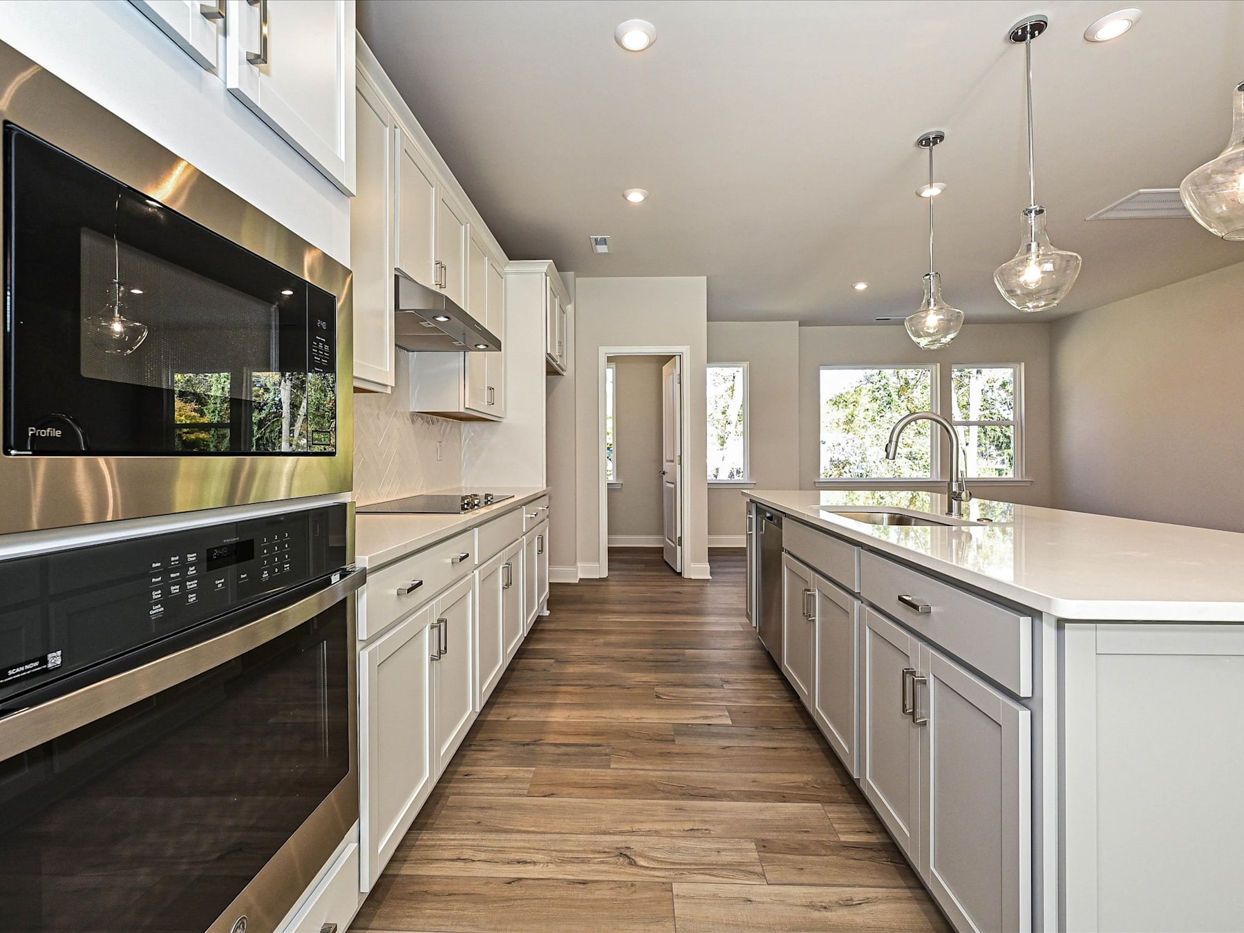 A modern, well-lit kitchen with white cabinets, stainless steel appliances, and a wooden floor, creating a bright and spacious atmosphere.