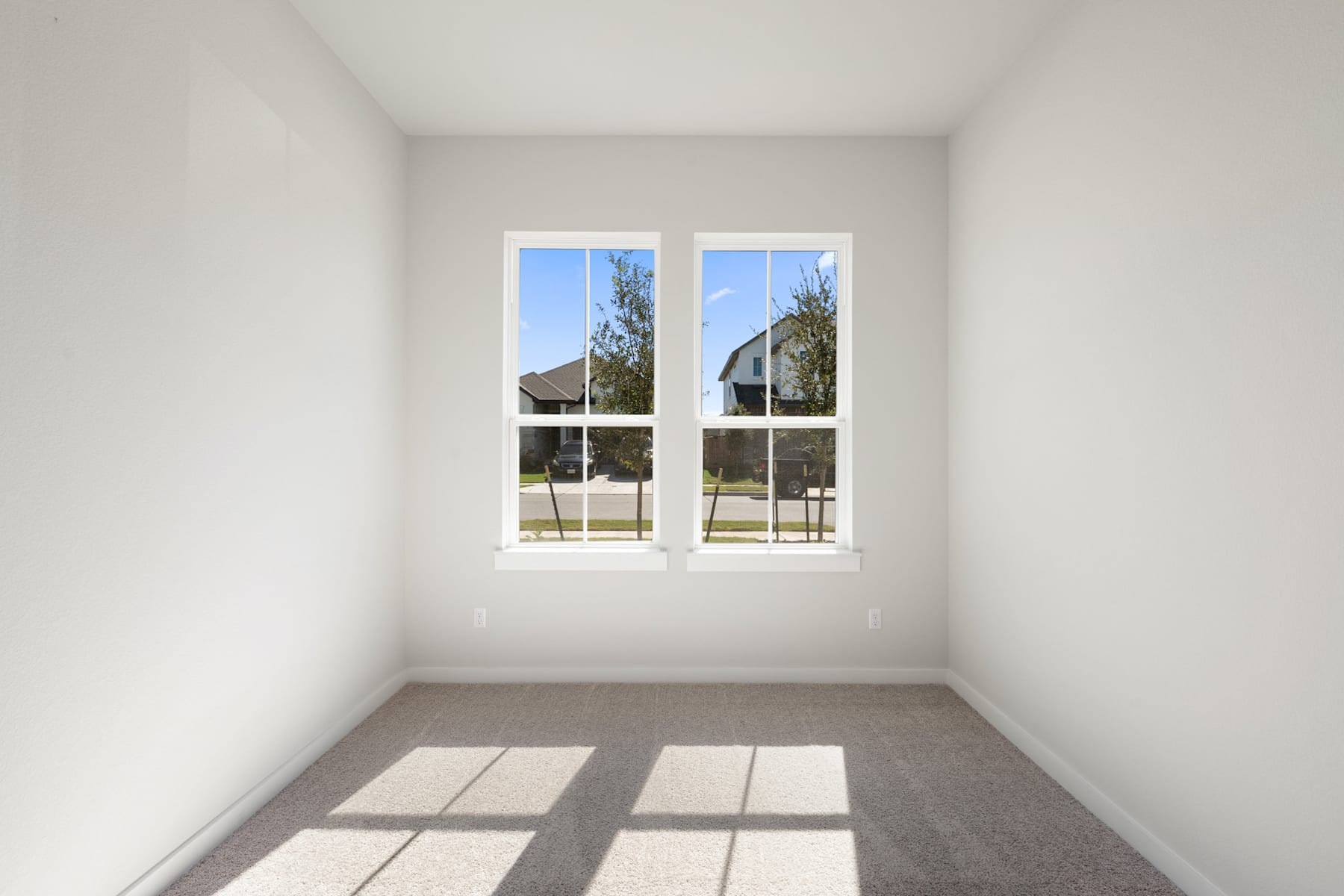 A bright, empty room with large windows overlooking a scenic outdoor landscape.