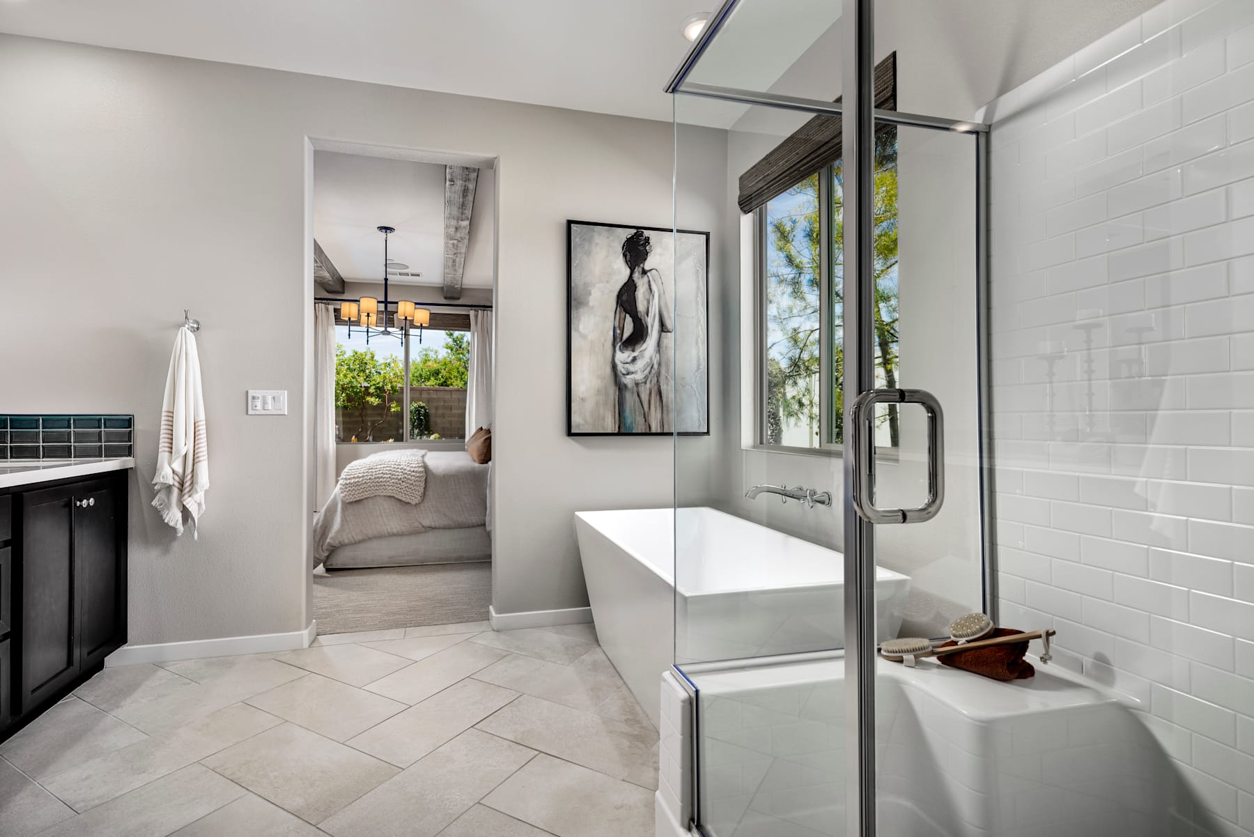 A modern, minimalist bathroom with a white vanity, glass shower enclosure, and a framed artwork on the wall, overlooking a lush outdoor view through a large window.