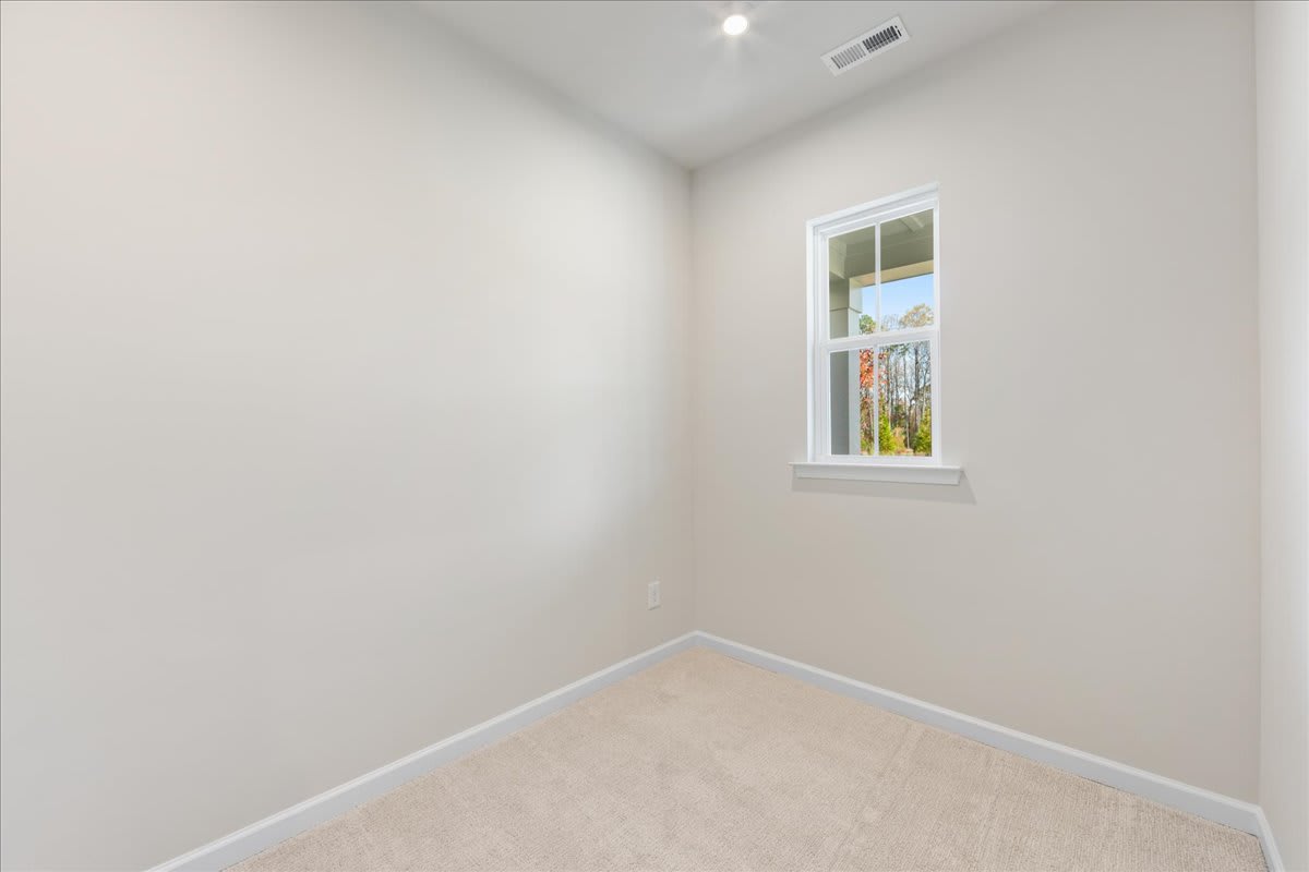 A bright, empty room with a window overlooking a scenic outdoor landscape.