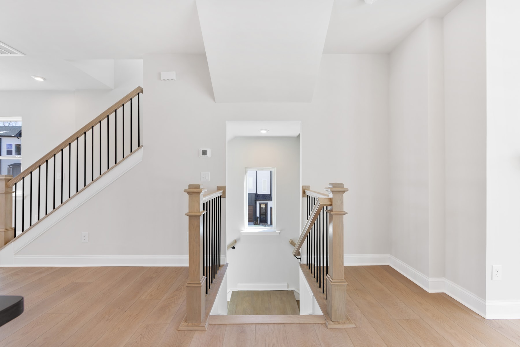 A bright, open staircase with wooden railings and floors leads to a hallway in the background, creating a welcoming and spacious atmosphere.
