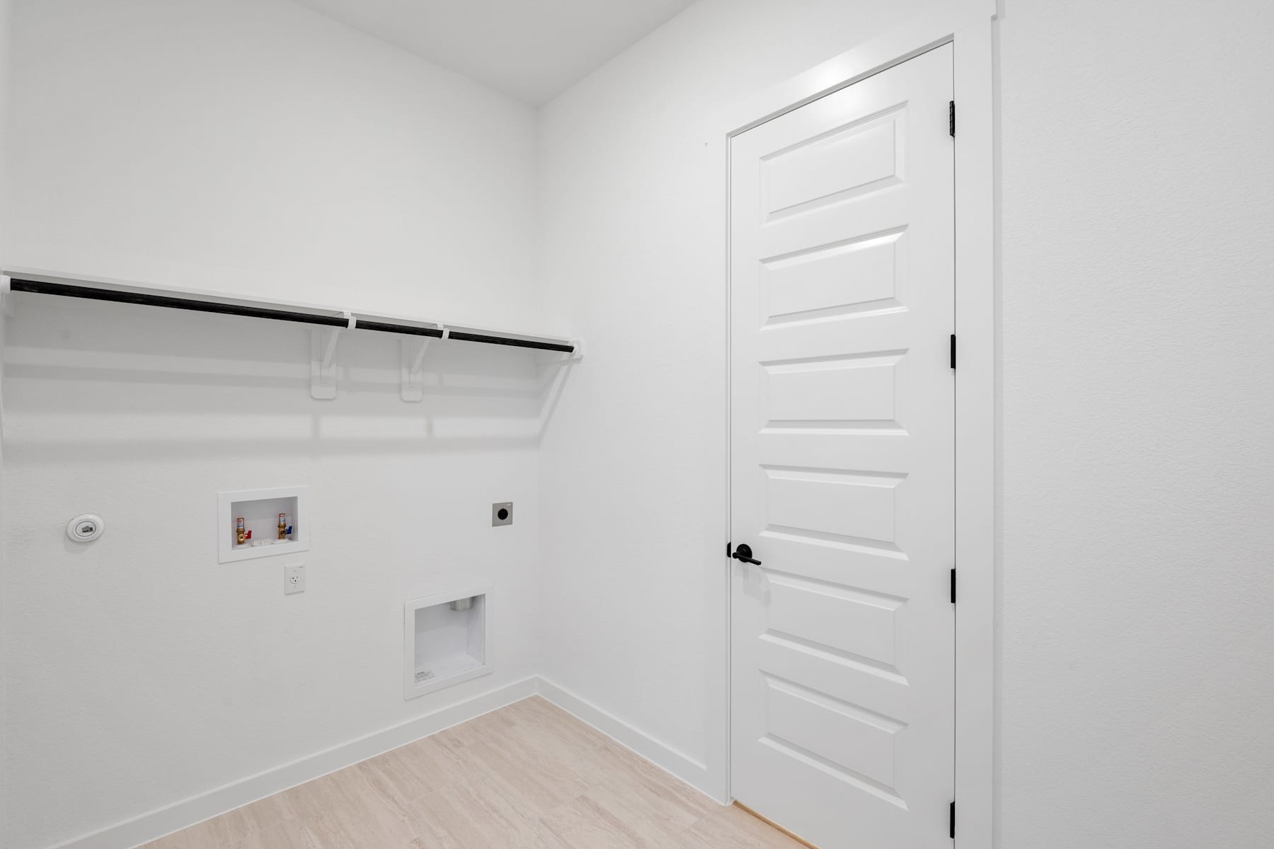 A simple, minimalist closet space with a white door, a clothing rod, and a clean, bright interior.