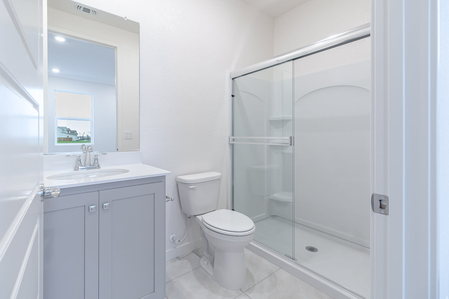A modern, minimalist bathroom with a vanity, toilet, and glass-enclosed shower, all in a clean, white color scheme.