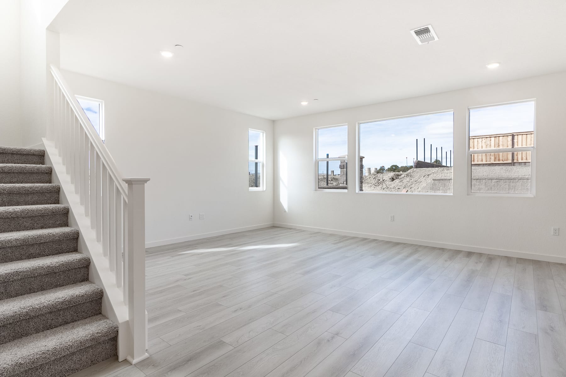 A bright and spacious interior with a staircase leading up to a landing, surrounded by large windows offering a view of the exterior landscape.