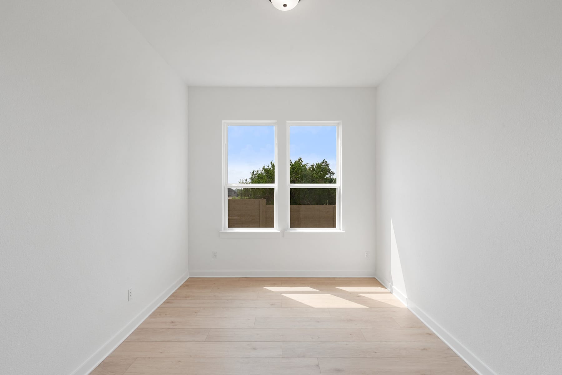 A bright, minimalist room with a large window overlooking a wooded area outside.